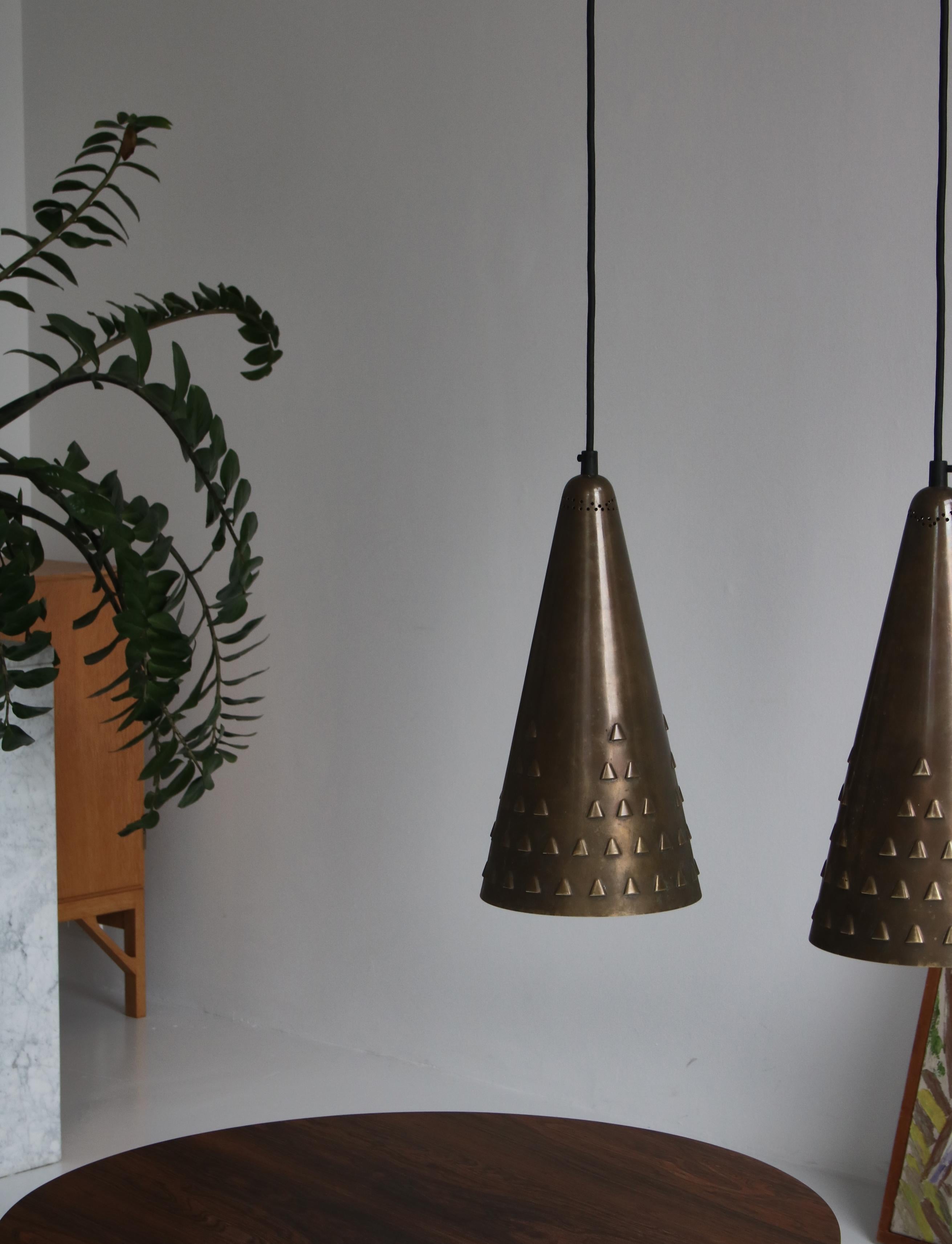 Pair of large brass pendants by Danish designer Brockmann-Petersen made for his stand at the Cabinetmakers Guild Exhibition in 1953. The large cone shaped shades are made from solid brass and are white lacquered on the inside. Both lamps have a nice