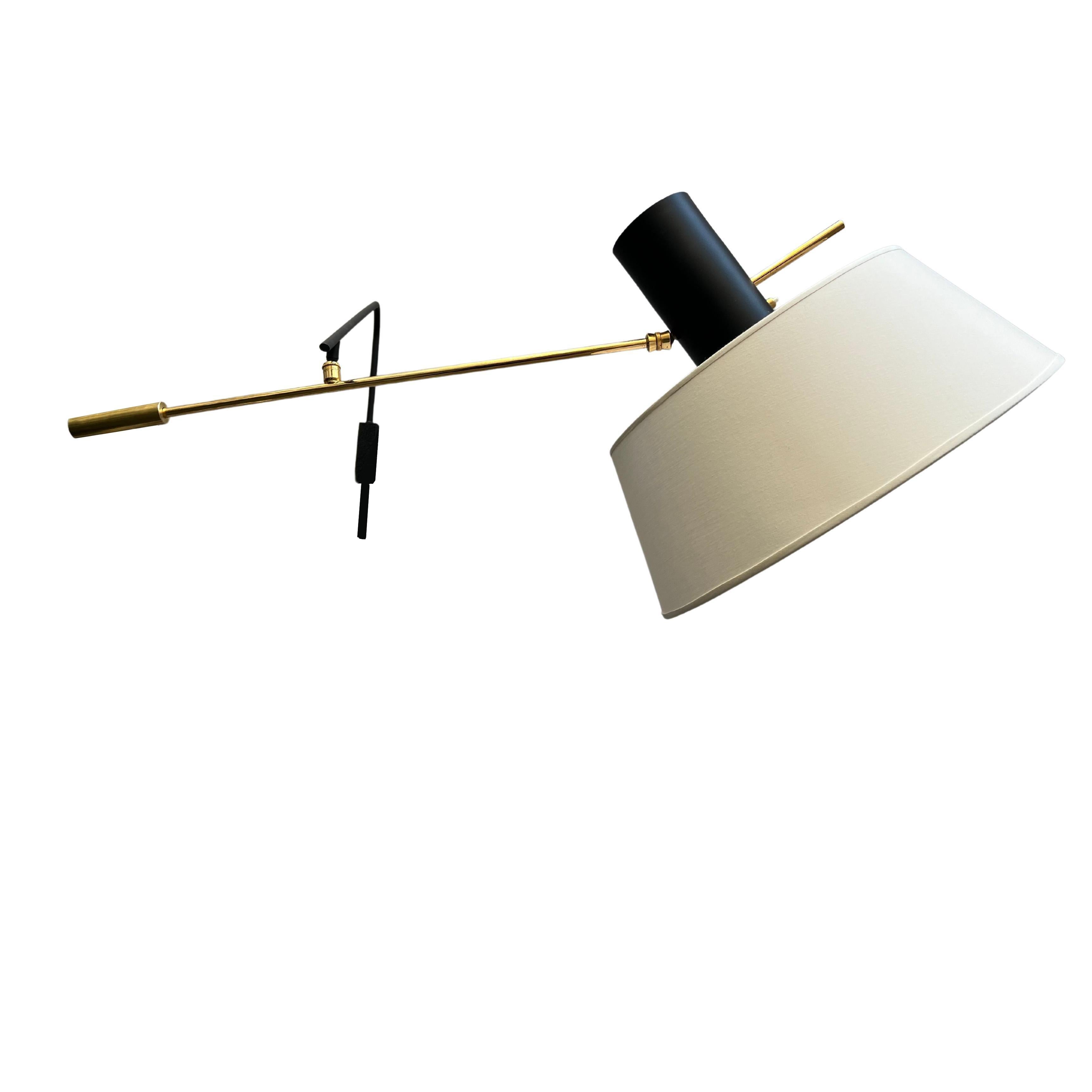 Rare Maison Lunel sconce with inverted shade, designed and produced circa 1960. 
Composed of a black-lacquered metal arm with wall mounting, terminated by a brass ball joint supporting the second arm fitted at one end with a brass counterweight, and
