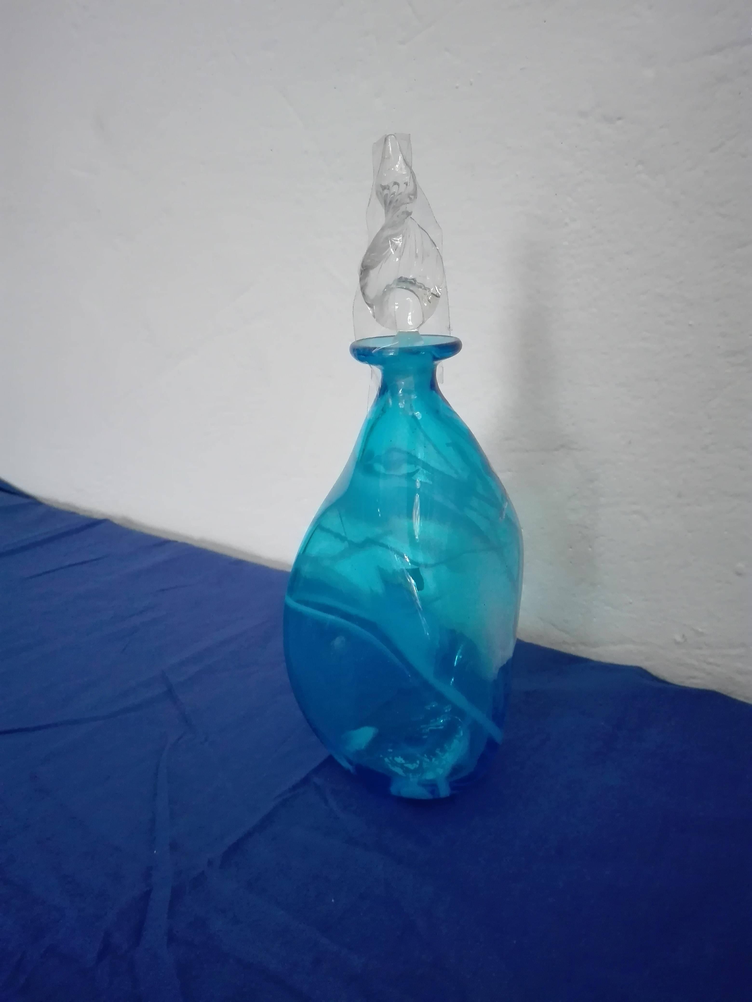 Murano glass bottle of white and light blue color with leaf cap. These magnificent glass objects are entirely handcrafted by our famous Venetian glass masters, who together with his collaborators give light to amazing unique, original and inimitable