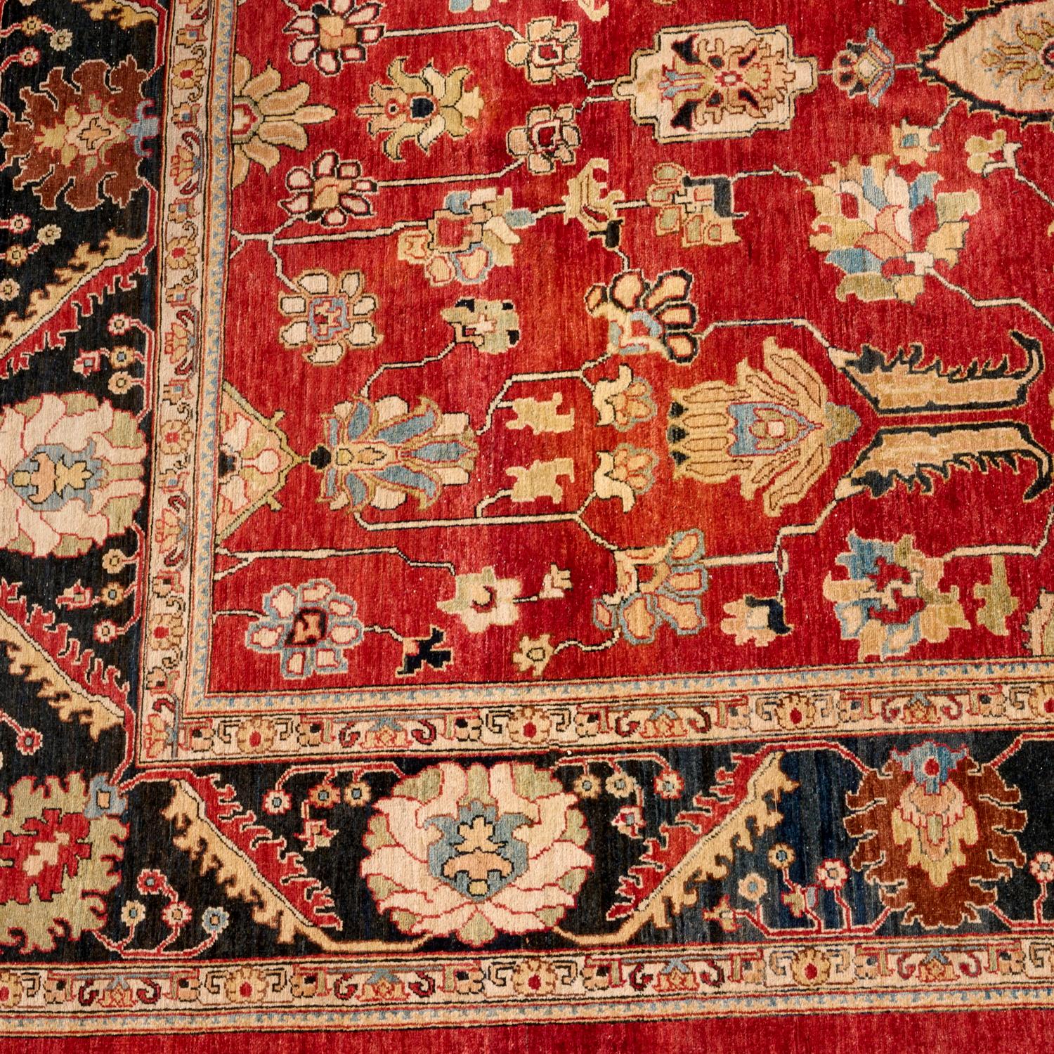 Alfombra persa de lana anudada a mano, de mediados del siglo XX, ricamente coloreada, con un saturado campo rojo rubí y un ornamentado borde añil. El diseño se inspira en los motivos clásicos Ziegler Sultanabad y Heriz, con una disposición simétrica