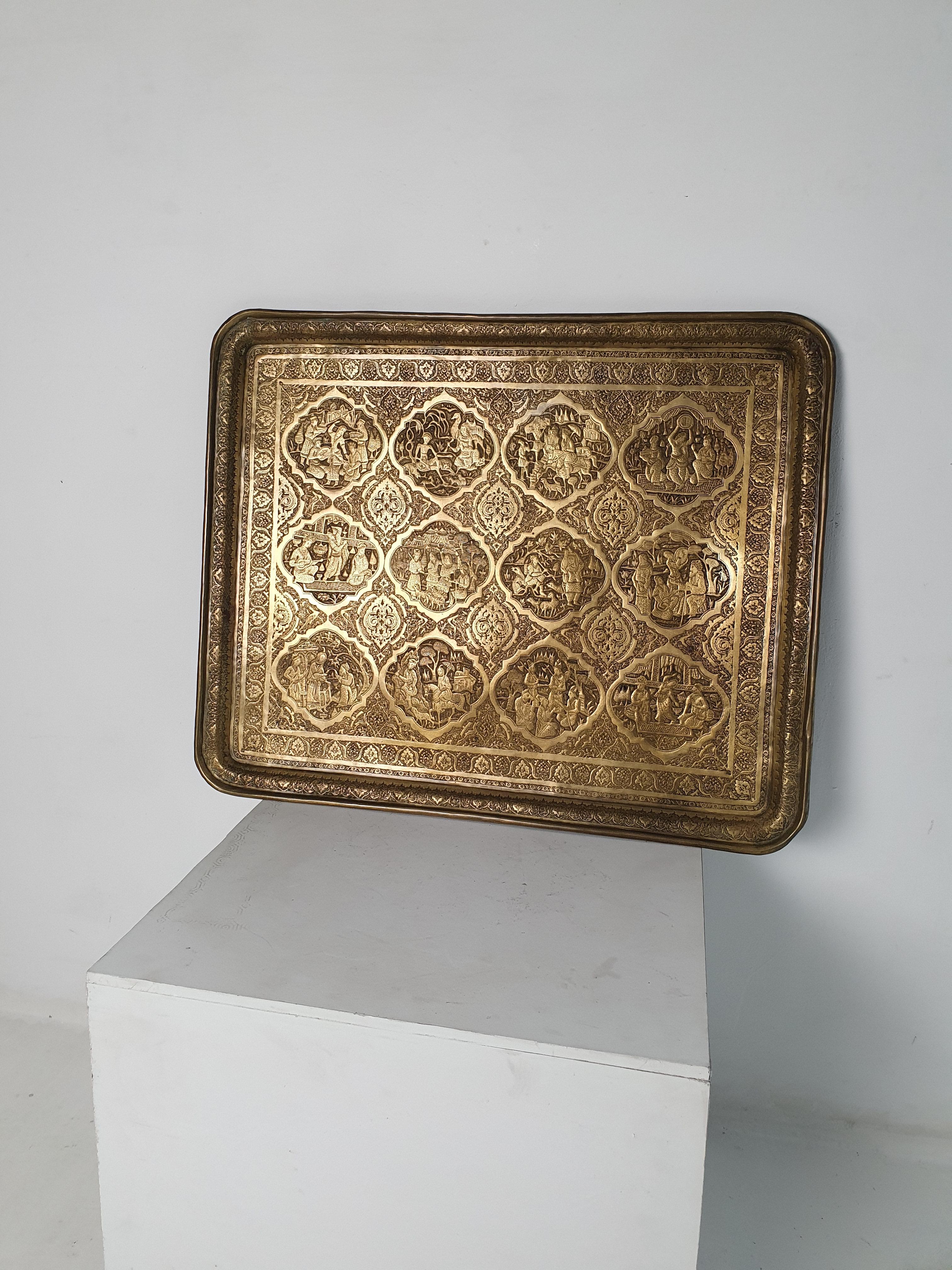 Behold this stunning piece from the Qajar dynasty - a large rectangular brass tray with rounded corners. This masterpiece was created using the intricate ghalamzani technique, which involves wrought and engraved décor featuring motifs from Persian