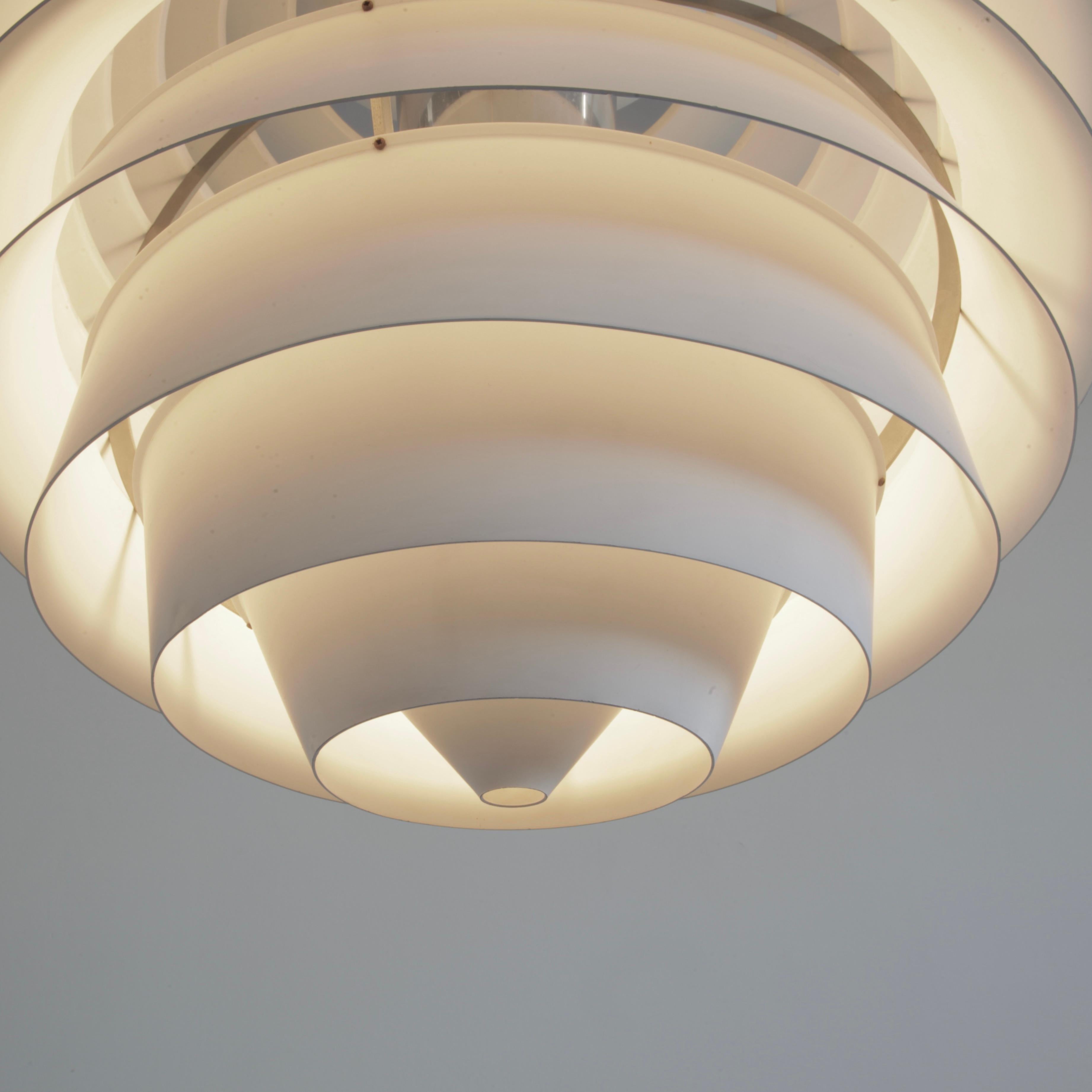 Ein früher Vintage-Anhänger LOUVRE von Poul Henningsen. Dänemark, Louis Poulsen, 1957.

Verchromter Rahmen mit weiß lackierten, runden Aluminiumlamellen. Der verchromte Mittelteil nimmt die höhenverstellbare E27-Leuchte auf. Das ursprüngliche Label