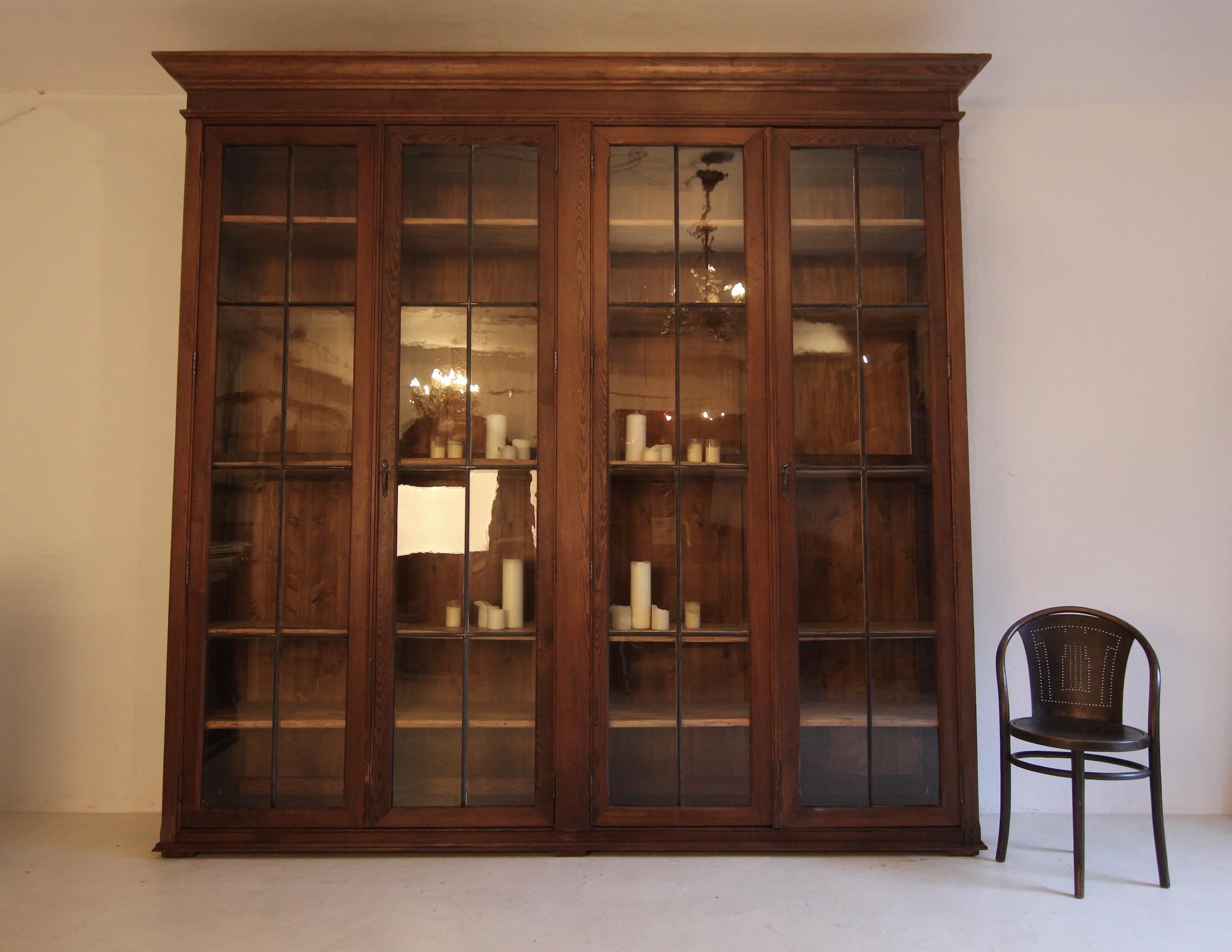 Large shop display cabinet or bookcase from an old pharmacy. France, around 1900. Made of solid pine wood.

A stunning unique piece in a classic timeless design and with a beautiful original patina.

Tall pinewood body, cassetted at the sides, with