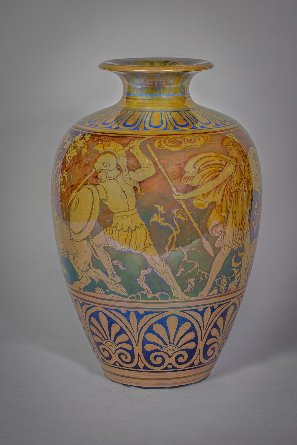 shouldered form with flaring neck, painted with a frieze of classical Greek warriors spearing a wild boar, between stylized foliage, in golden lustre on a blue and red ground, painted artist cipher of Richard Joyce and date.