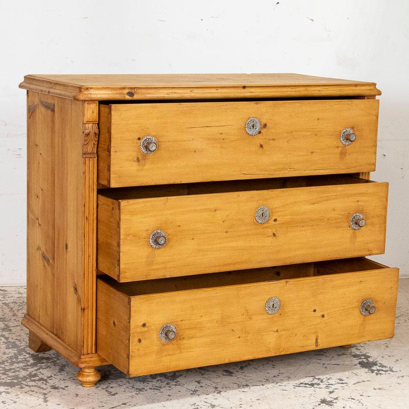 The beauty of this large Romanian chest of drawers is the simplicity of the lines and the 3 large, spacious drawers. The simple carved detail along the sides were a traditional style element of the period while the pressed tin hardware accents add