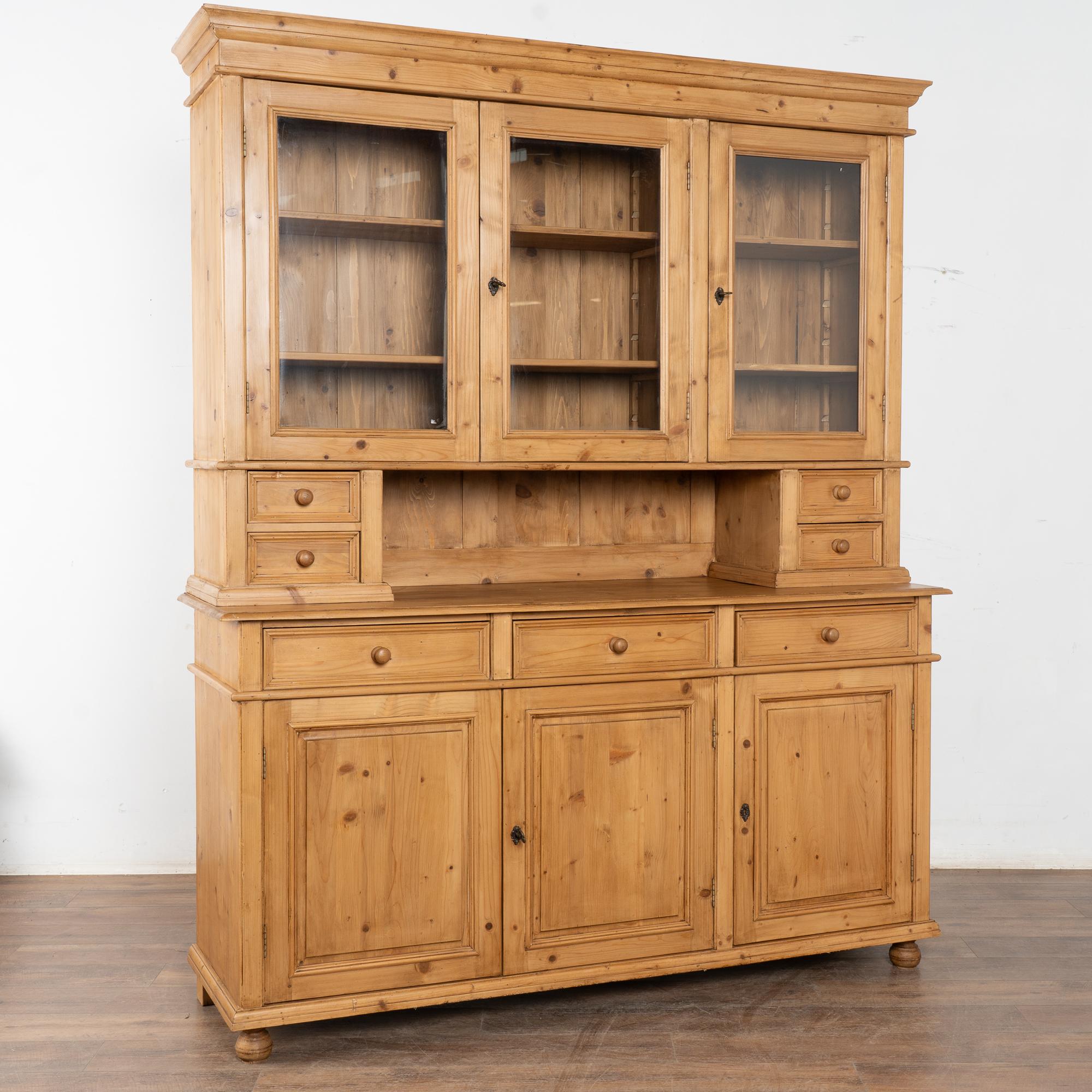 Diese große Vitrine aus Kiefernholz ist eine Reproduktion eines typischen Schranks aus den 1800er Jahren in Europa und lässt sich zum leichteren Transport und Aufbau in zwei große Teile zerlegen.
Das Kiefernholz hat eine warme, einladende Patina und