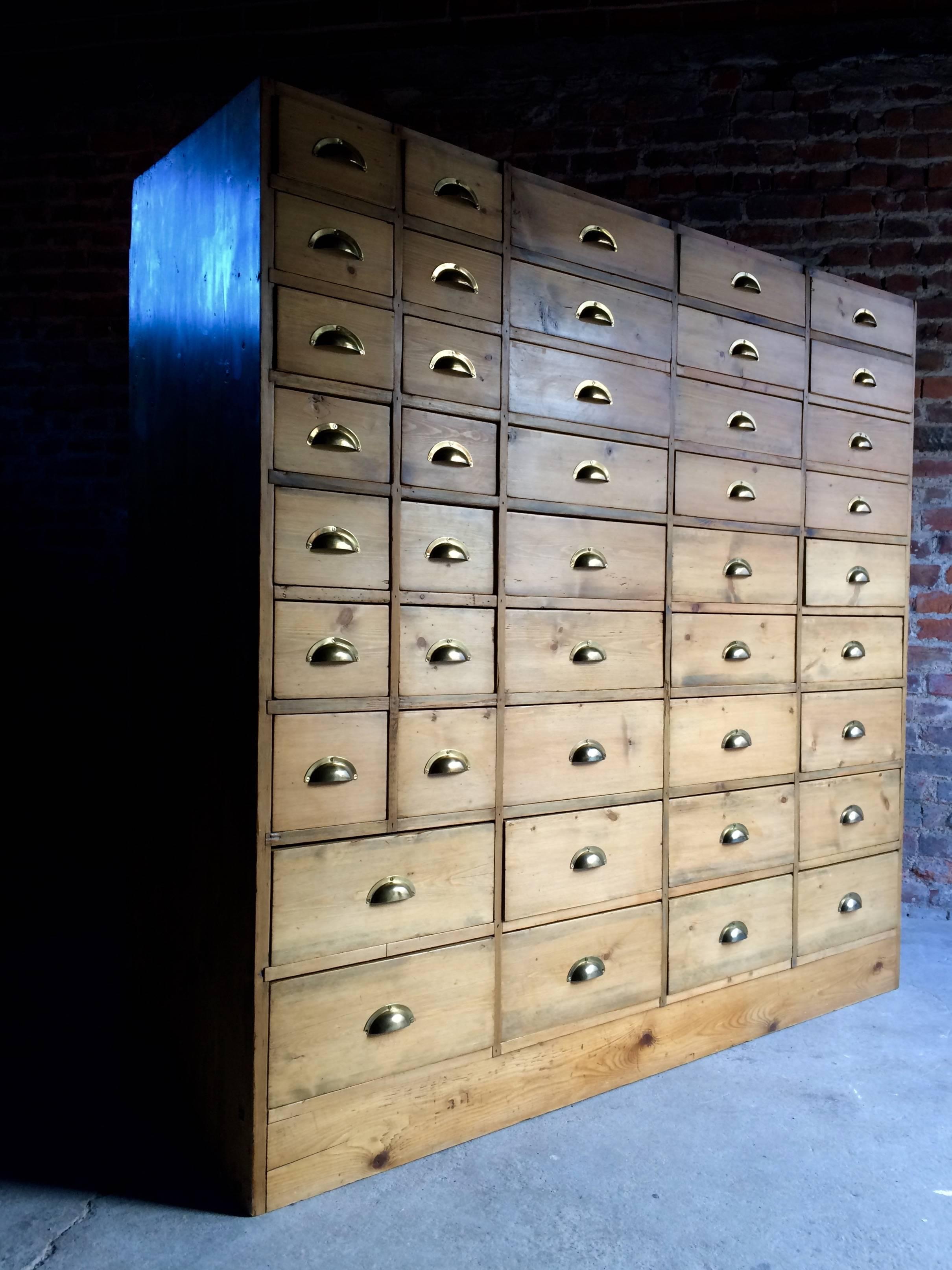 A magnificent large waxed pine haberdashery chest of drawers, compromising an arrangement of 43 drawers in total, all with brass cup handles, raised on plinth base, please note this is extremely large and heavy and will require at least two-three