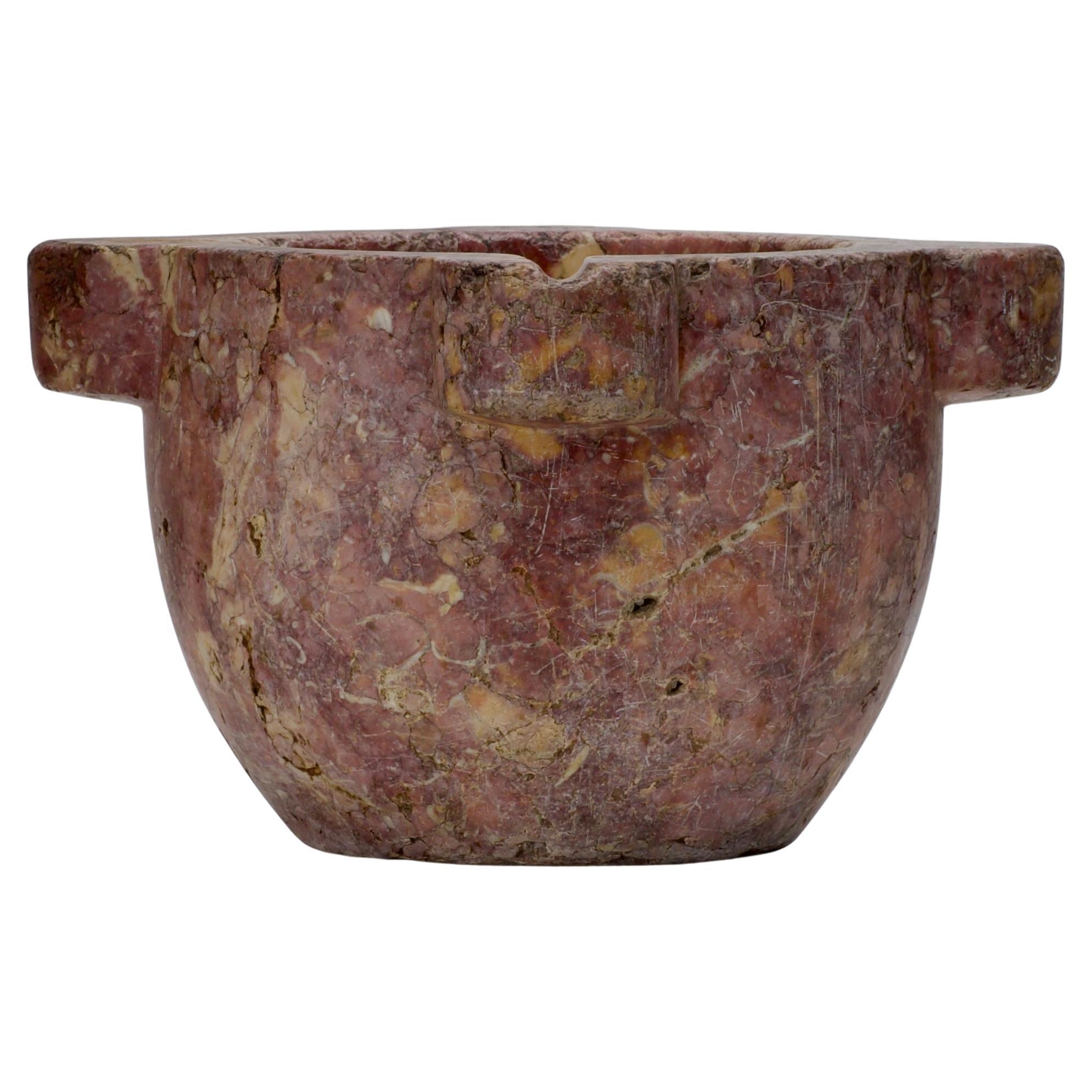 This French marble mortar is an impressive piece that blends historical craftsmanship with natural beauty. Its massive, solid form is enhanced by a rare and striking color palette, featuring a warm interplay of rosy pinks, deep reds, and creamy