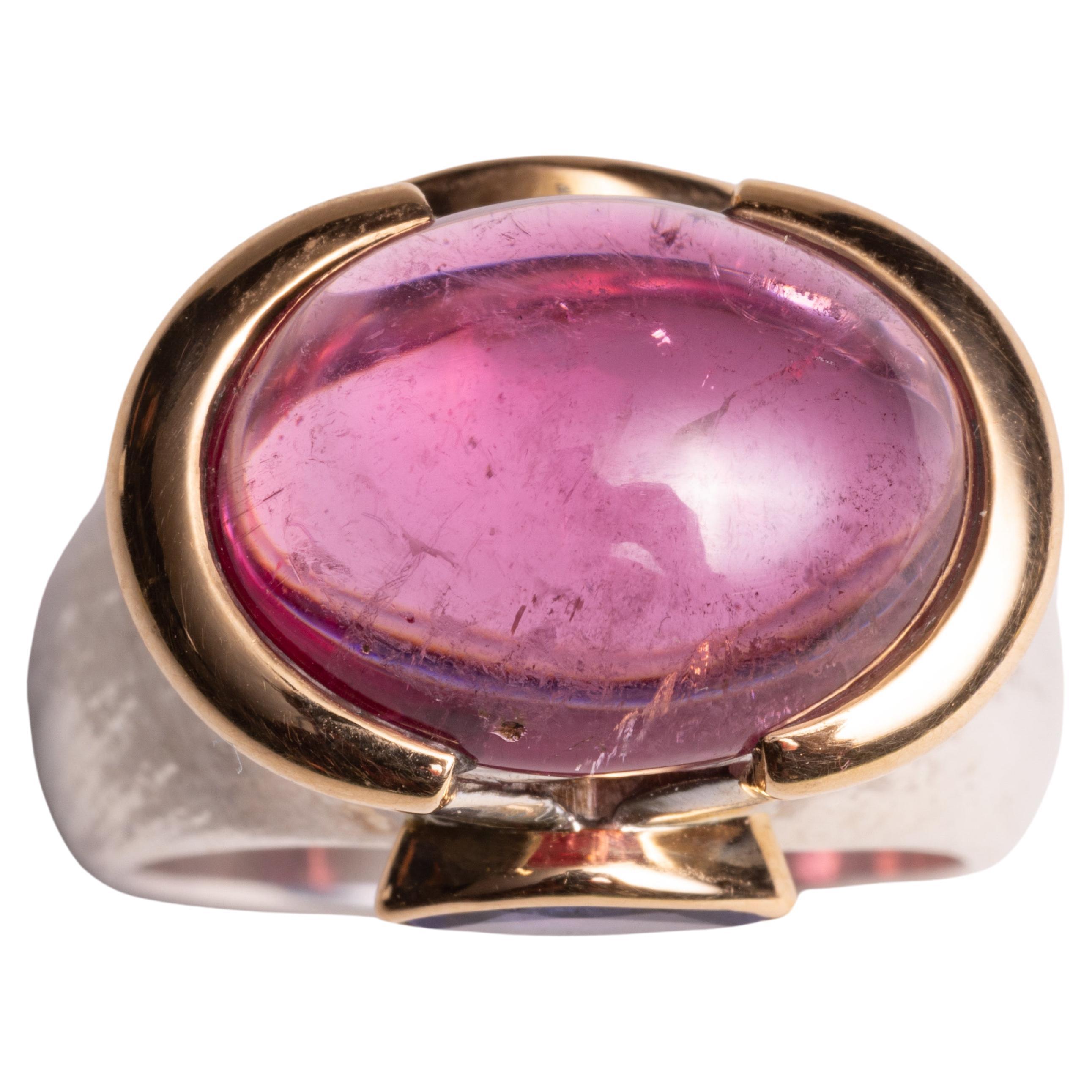 A spectacular large pink tourmaline cabochon dome ring set in 18K gold.  It is flanked by two marquise cut tanzanite stones also set in 18K gold.  The band itself is sterling silver.  Ring size is 7.25.

The fine jewelry collection is sourced,