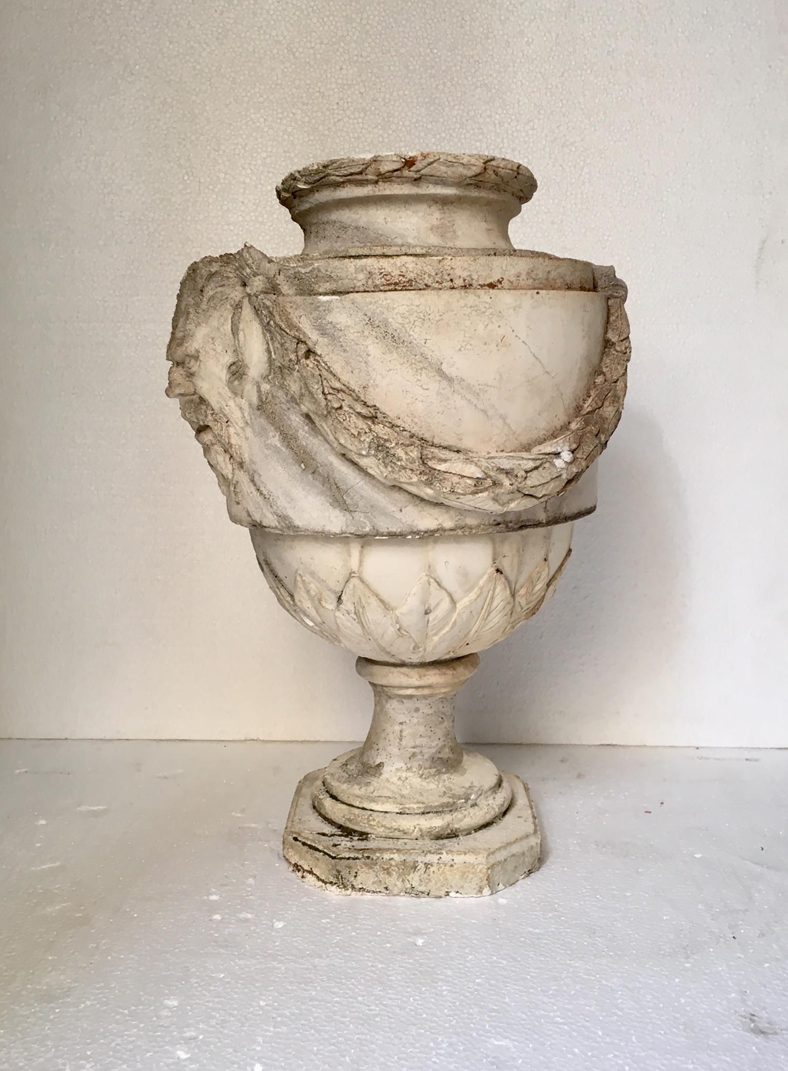 Large plaster vase in the style of antiquity, with decoration of vegetable garlands on the sides and heads of faun, is a very decorative element.