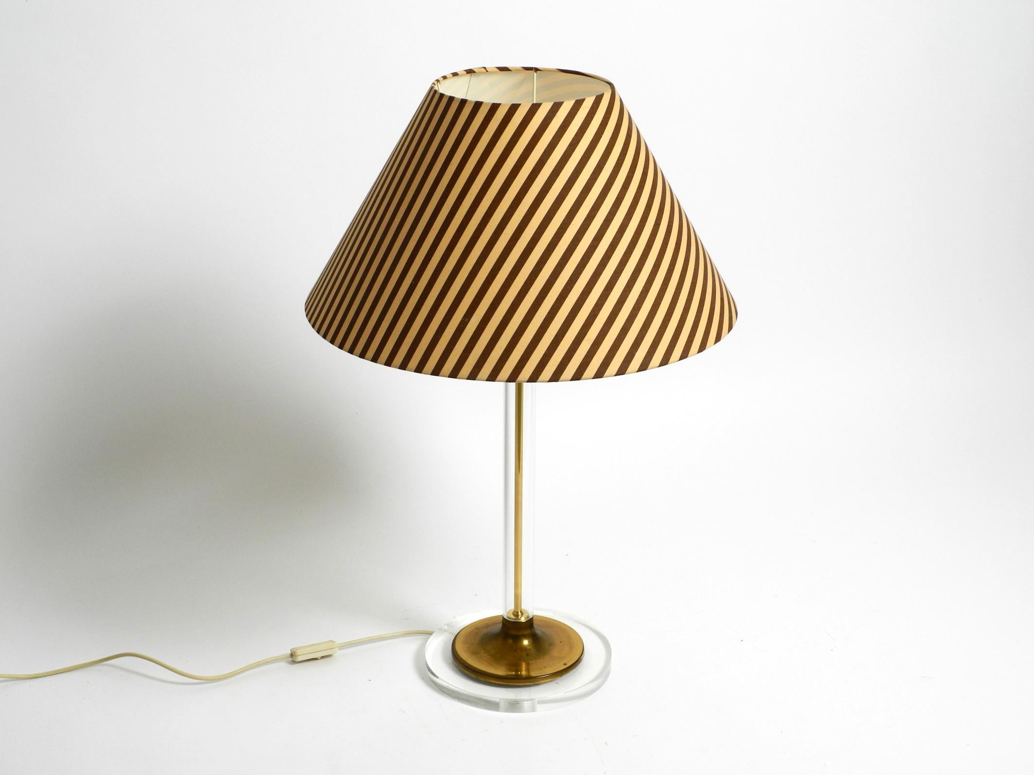Very rare large table lamp from the 70s made of plexiglass and brass.
Made by the Vereinigten Werkstätten. Made in Germany.
Very high quality minimalistic design. 
Base and neck are made of solid plexiglass. 
The cover on the base and the rod inside