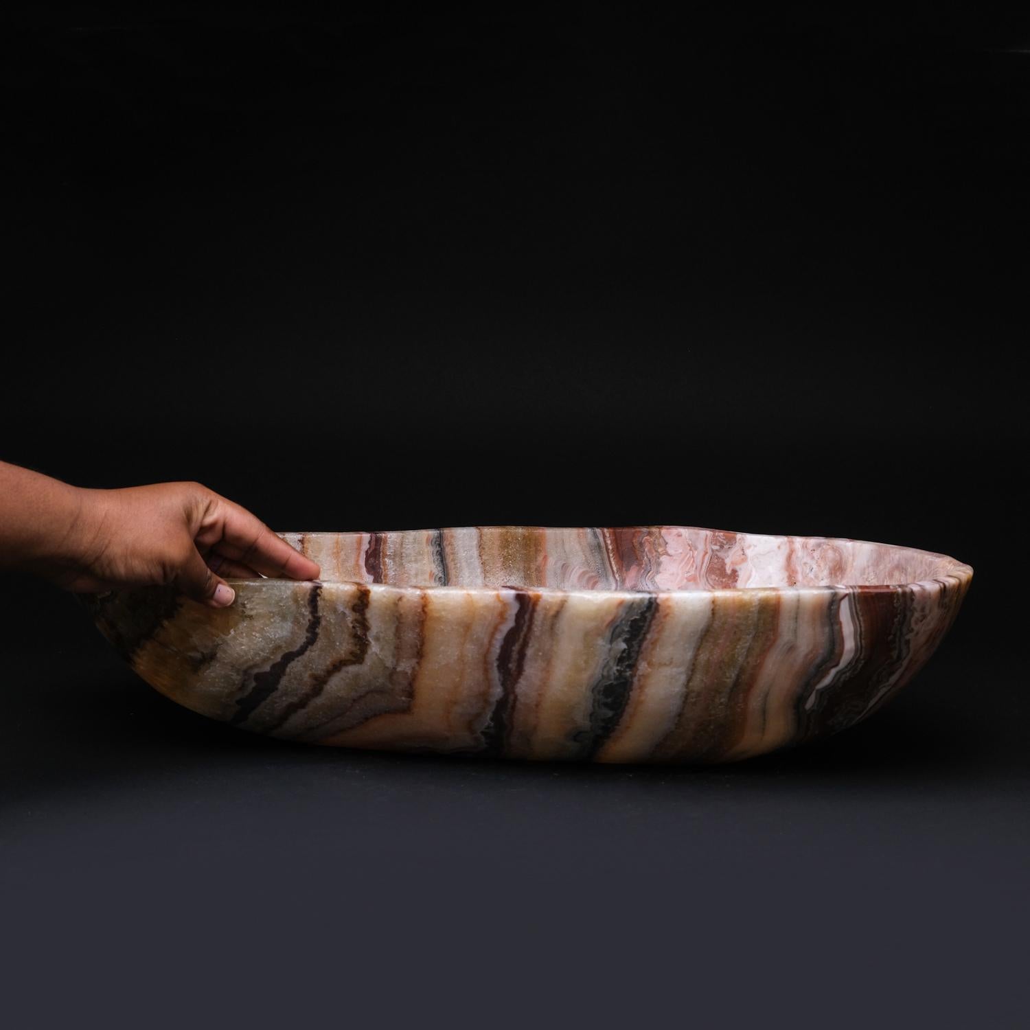 Large, one-of-a-kind, free-form natural rainbow onyx canoe bowl carved out of a single chunk of banded natural onyx. This incredible translucent piece is hand polished to a mirrored finish. This unique piece blends natural onyx shades of green,