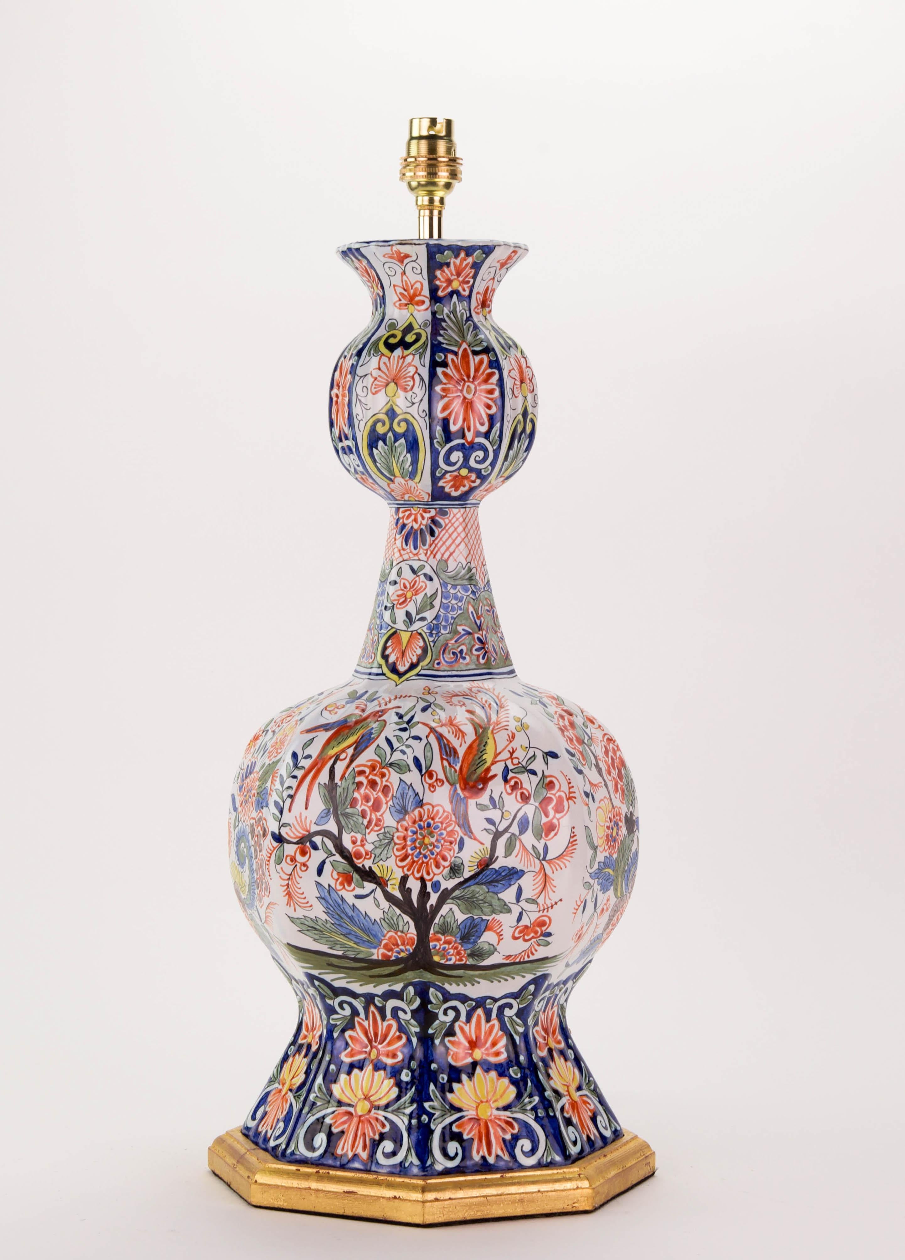 A fine Dutch Delft lamp, of hexagonal form, decorated in wonderful polychrome colours, with exotic birds in garden scenery.

Height of vase: 18 3/4 in (47.5  cm) including giltwood base, but excluding electrical fitments and lampshades.

All of