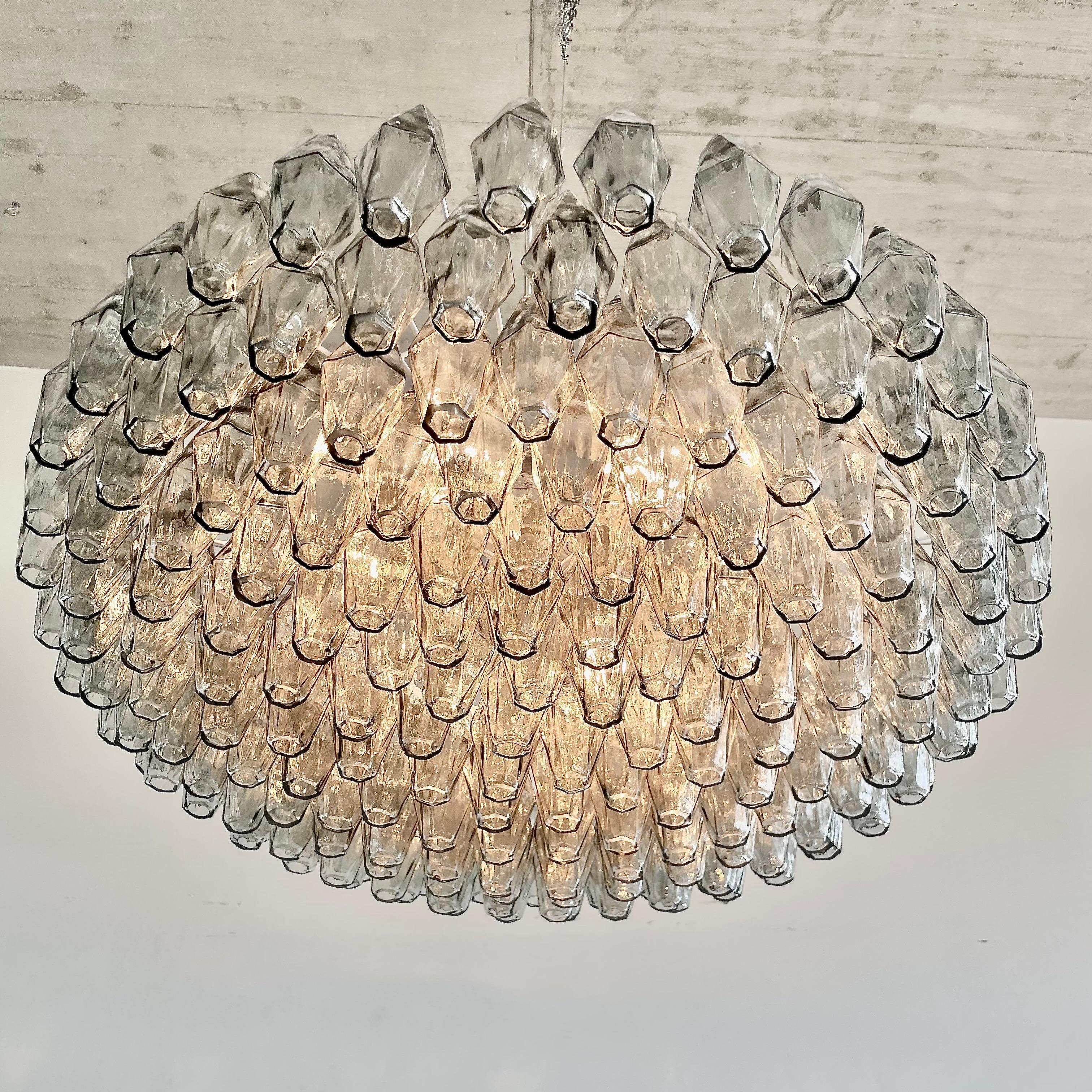 Chandelier with handblown grey glass pieces. Italy, Murano, 1990s.

Polyhedron chandelier with a white metal frame and nearly 200 polyhedron glass pieces in amber. Six E27 light sockets, metal cable for hanging.

Please note: All lighting fixtures