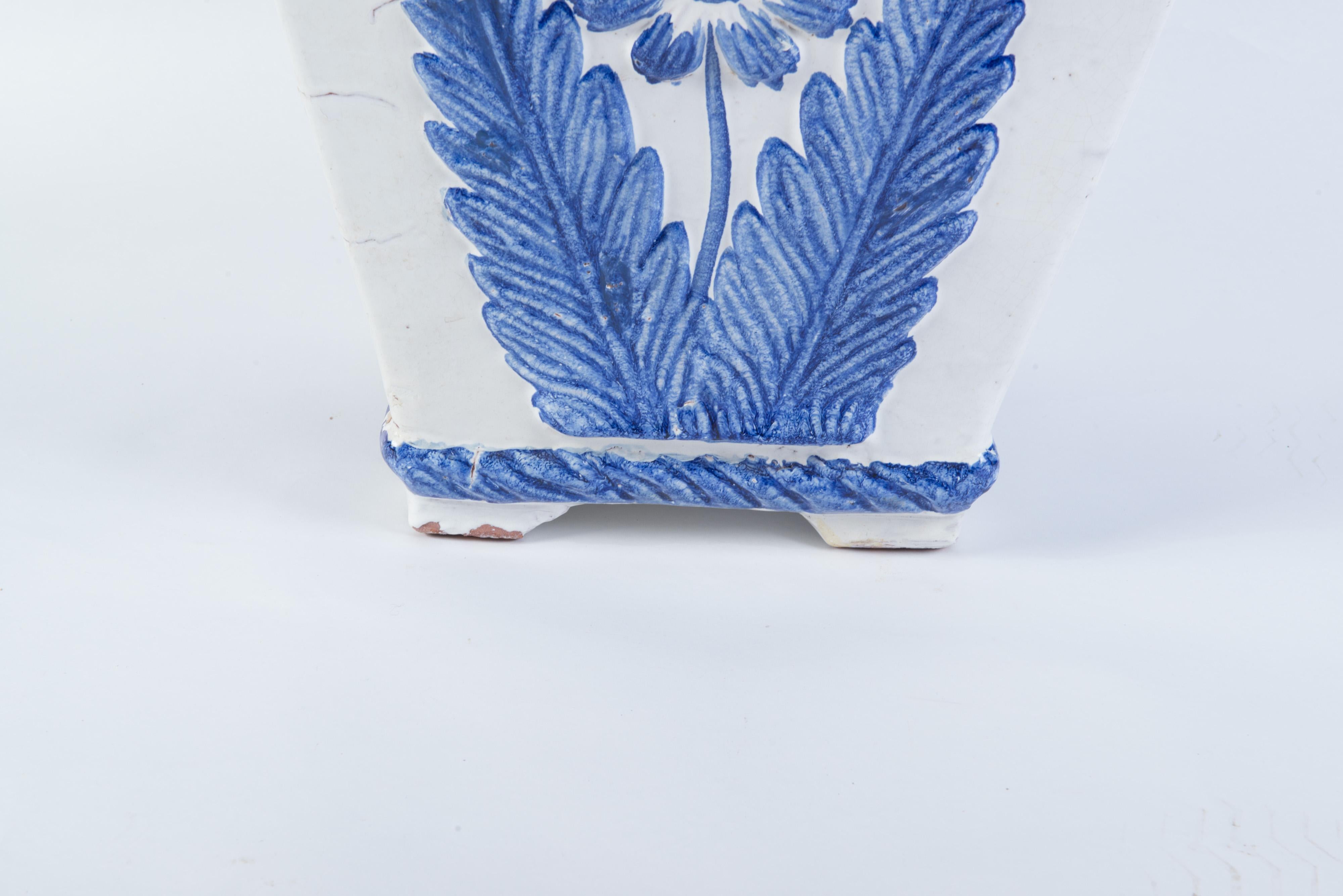 Jardinera de terracota vidriada azul y blanca de buen tamaño, procedente de Portugal. Gran flor azul estilizada en cada lado. Decoración estilo huevo y dardo alrededor del borde superior. La medida de la base es de 9 pulgadas cuadradas.
