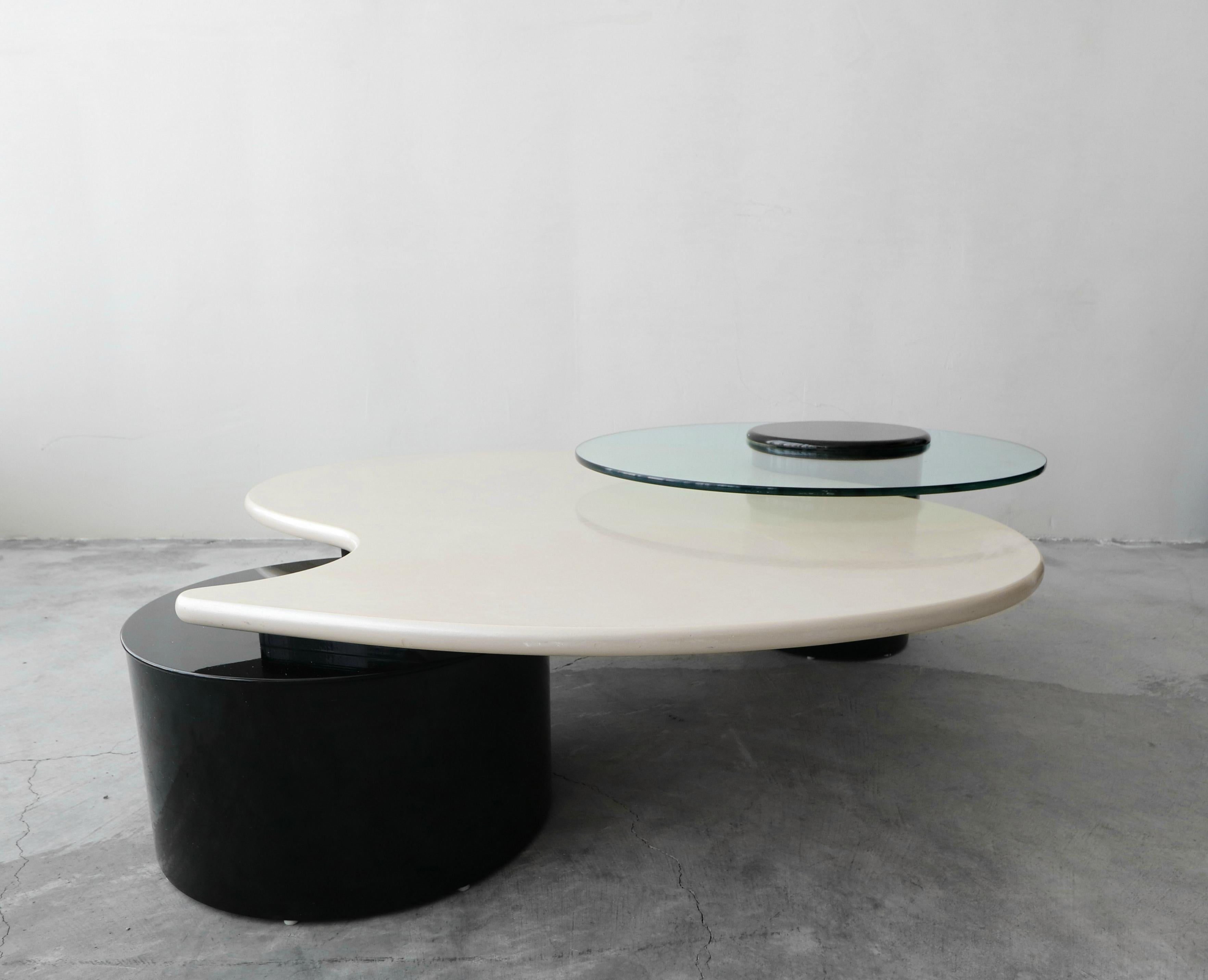 Beautiful and large Postmodern coffee table by Rougier. The table is black gloss and pearlize white lacquer with and articulating piece of glass. Very unique and different piece. Perfect for a rounded sofa or seating configuration.

Table is in