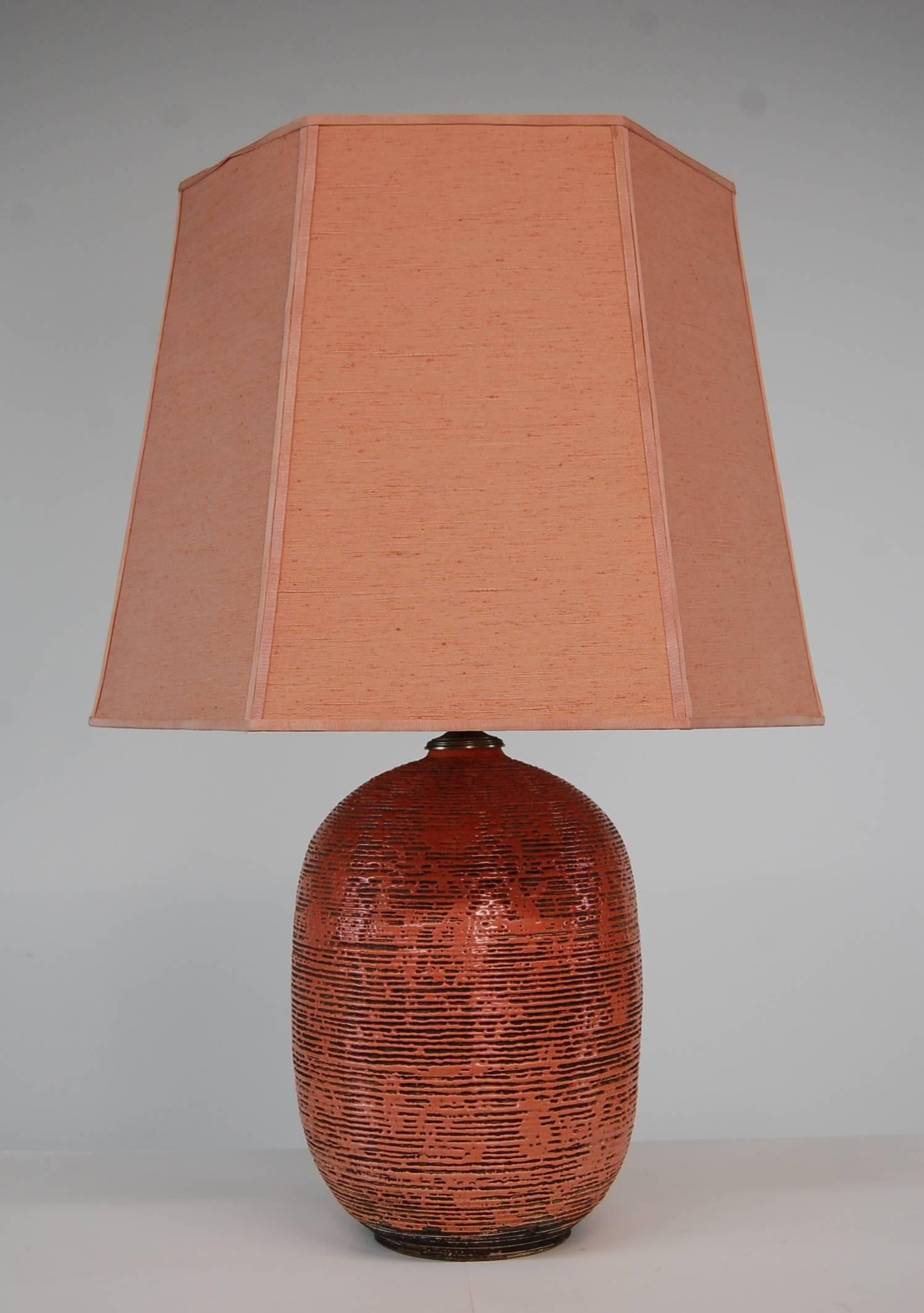 Pottery lamp, circa 1935, in the manner of Jean Besnard. Salmon color salt glaze is stunning. High quality nickel plated hardware for regular lighting, up lighting, or both. Custom salmon colored linen shade. Measures: Stands 34