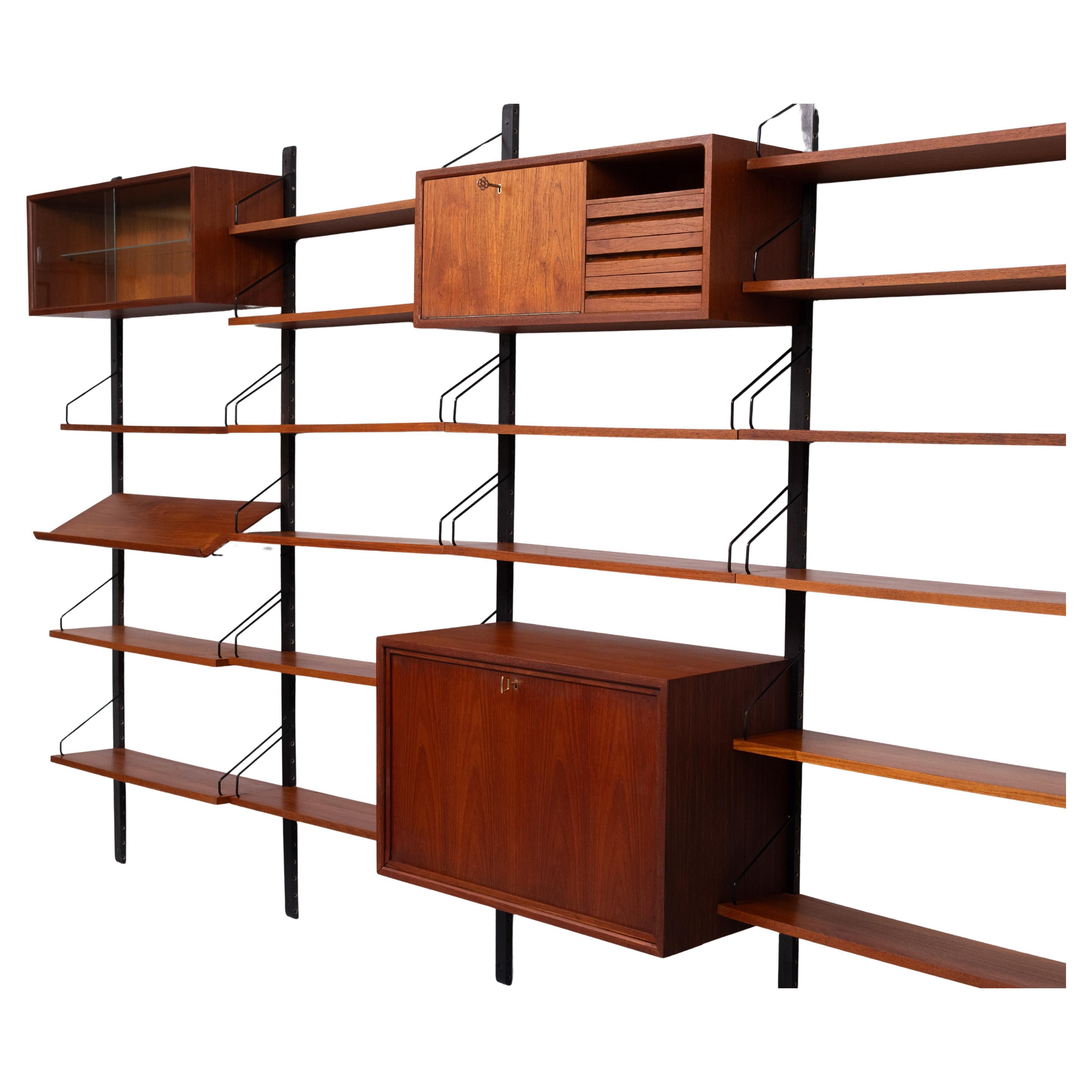 Sistema a parete in teak Iconic di grandi dimensioni. 5 montanti. 3 armadi e 17 ripiani, e il raro scaffale per riviste viene fornito con tutta la ferramenta.
Questo sistema modulare può essere modificato in tutti i modi che desideri. Ideale per
