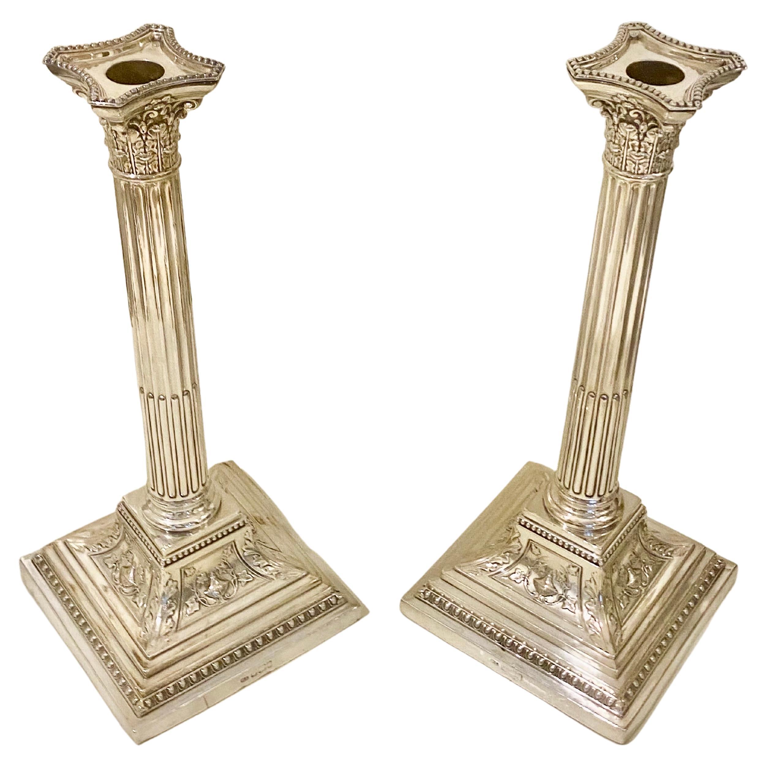 An impressive, large pair of antique Victorian English sterling silver Corinthian column candlesticks; in the Neoclassical style. 
These exceptional antique Victorian sterling silver candlesticks have Corinthian columns to a knop and square swept