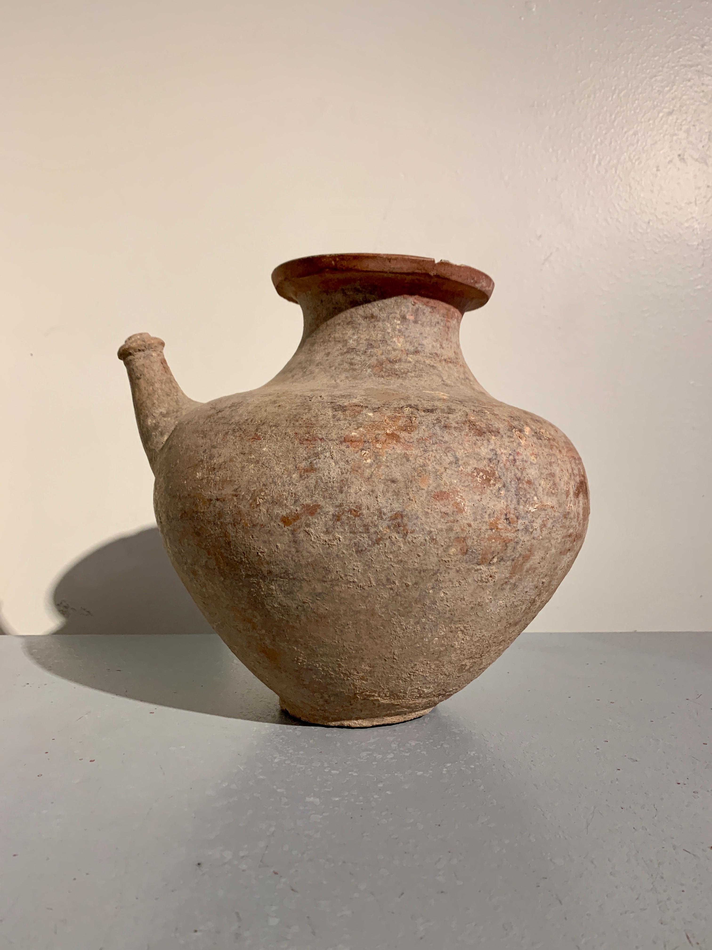 A large and attractive pre-Khmer red pottery kendi, pouring vessel, 6th - 8th century, Cambodia. 

The large vessel crafted of a red pottery, with a wide, globular body resting on a narrow, round, flat bottomed foot. A short, tapering neck rises