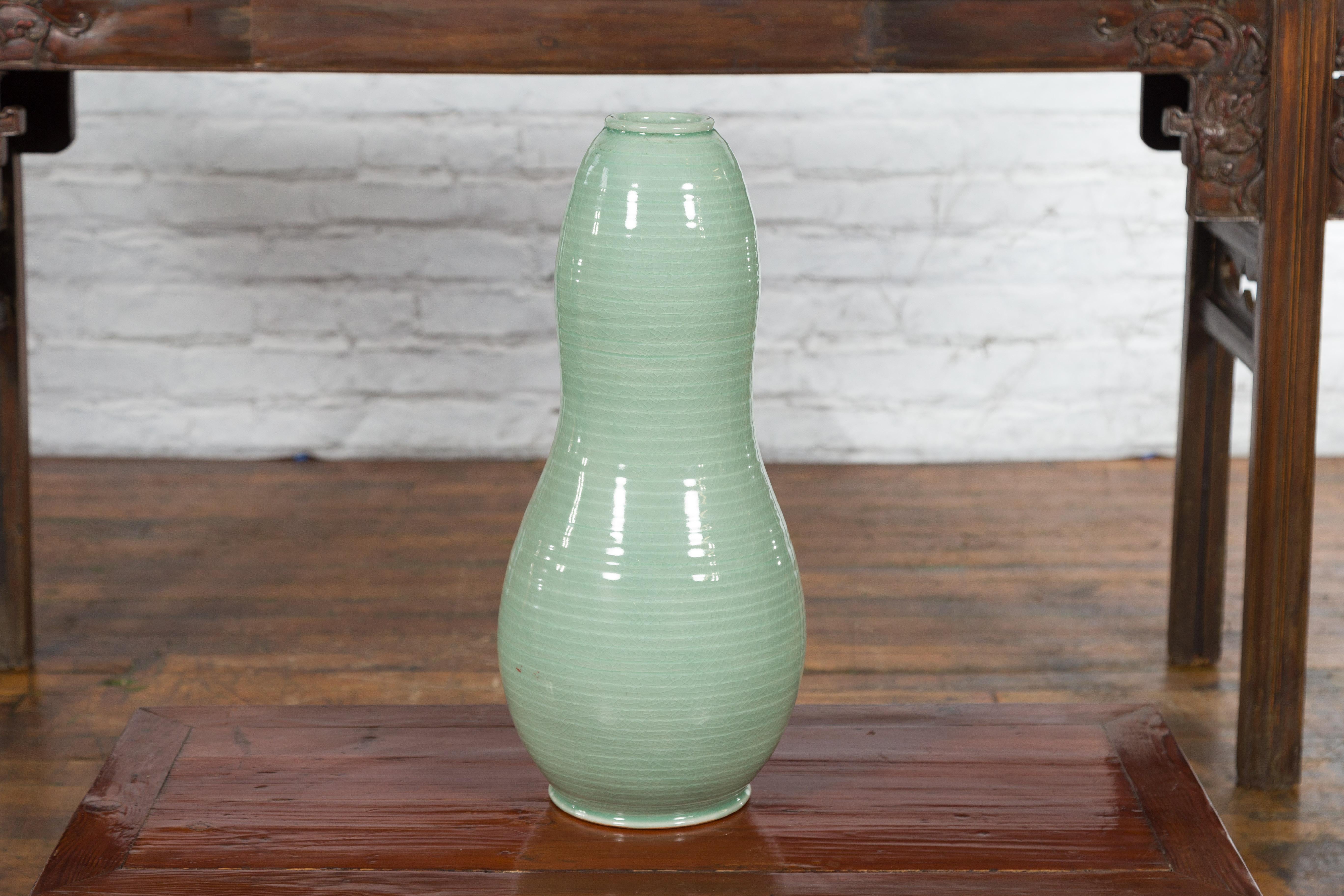 A large contemporary Northern Thai gourd-shaped vase from the Prem Collection, with green glaze. Charming our eye with its generous lines and soft color, this vase was created in Chiang Mai, northern Thailand. Showcasing concentric patterns adorning