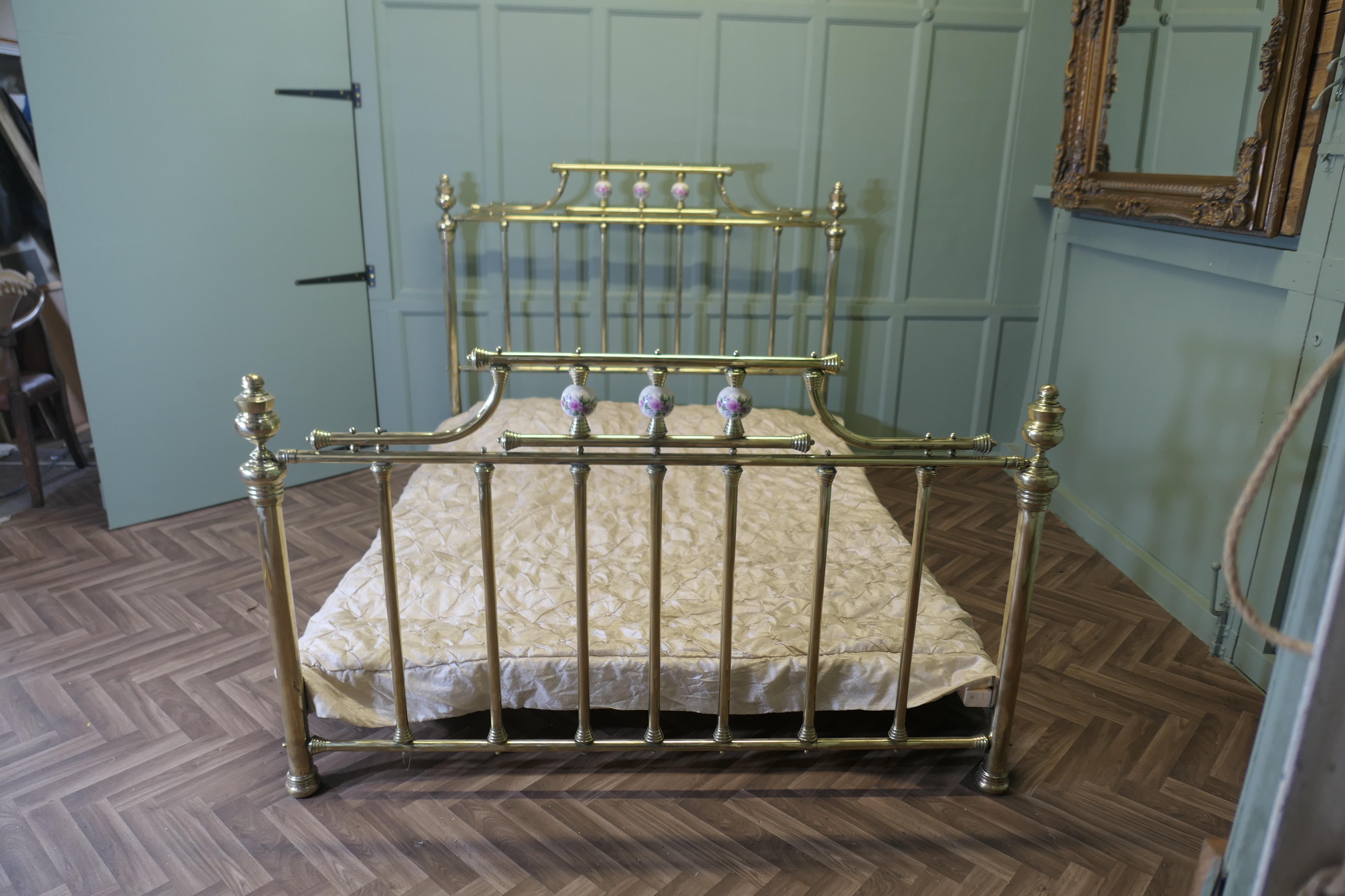 Large Pretty King Size Brass Bed

The head of the bed has decorative painted ceramic spheres and brass spindles, matching similar decoration at the foot, both ends have turned brass knobs 
The bed is good quality and is in excellent condition, it is