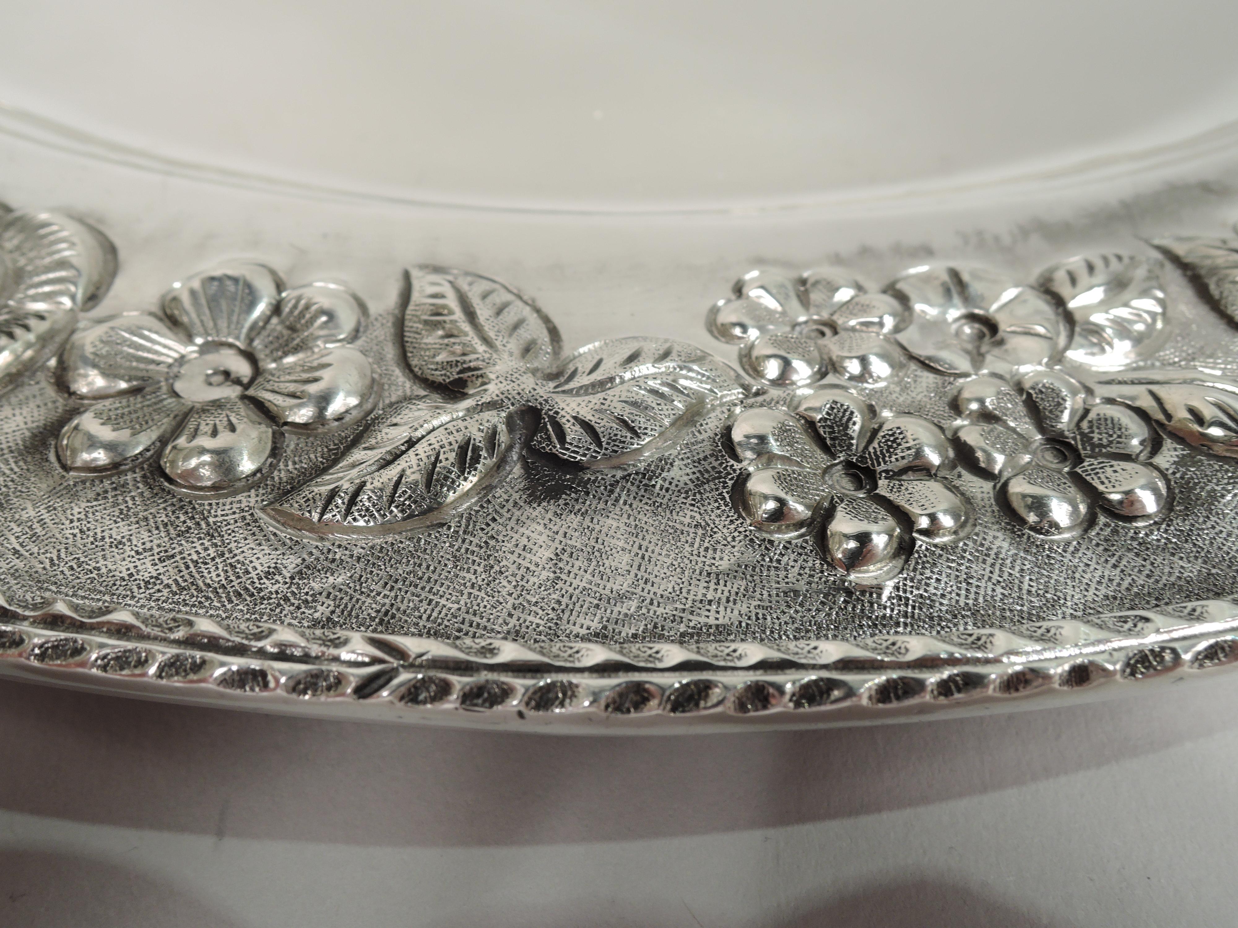 Large and pretty silver tray. Round and plain well and wide shoulder with engraved and repousse garland; applied rim with leaf border. Marked. Visible handwork on underside. Weight: 39.5 troy ounces.