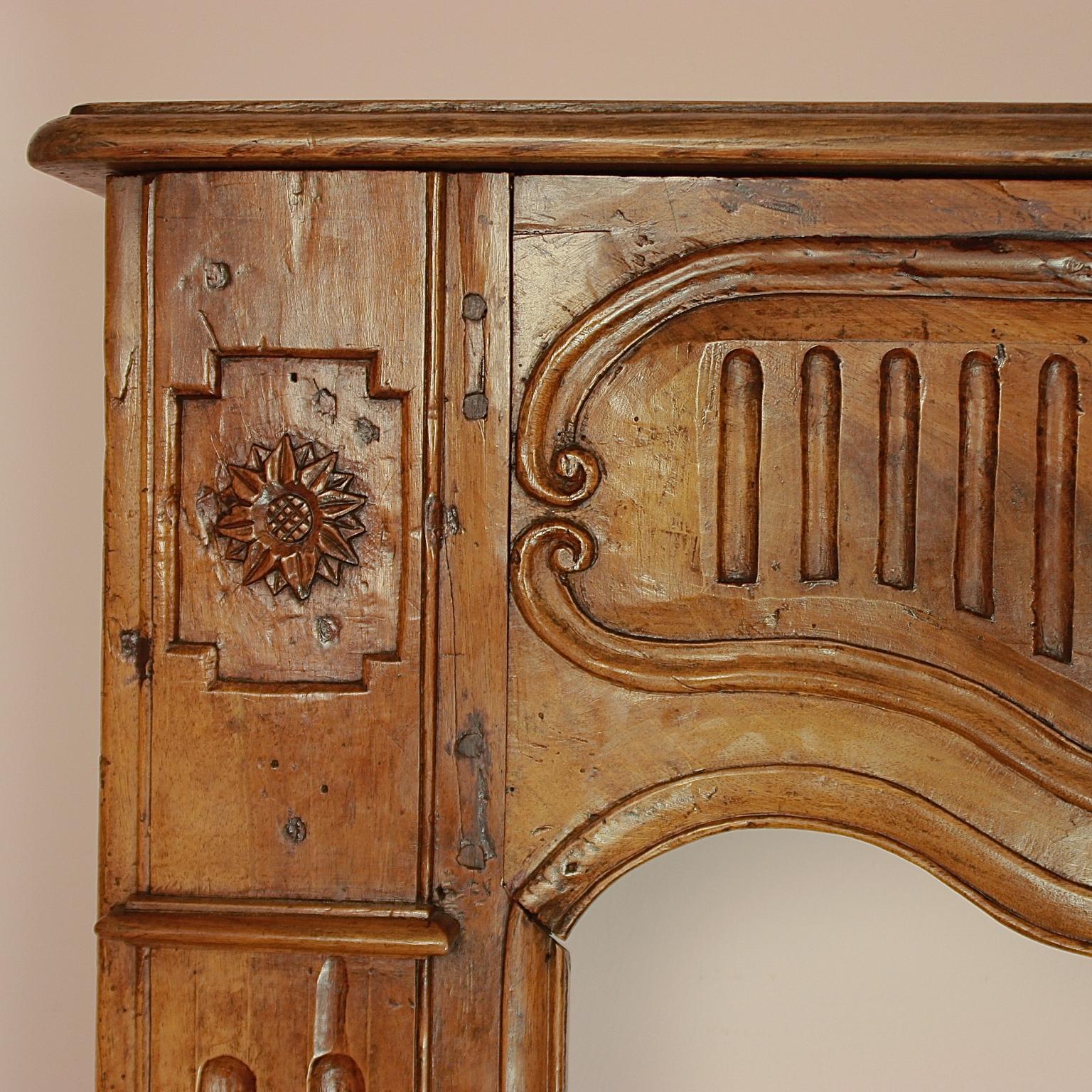 An exceptional large walnut fireplace surround measuring 7 feet and 8.1 inches (2.34 m) in width, carved in walnut with a beautiful patina. Originating from the Louis XIV period and crafted in a plain Provincial design. The surface accumulated a