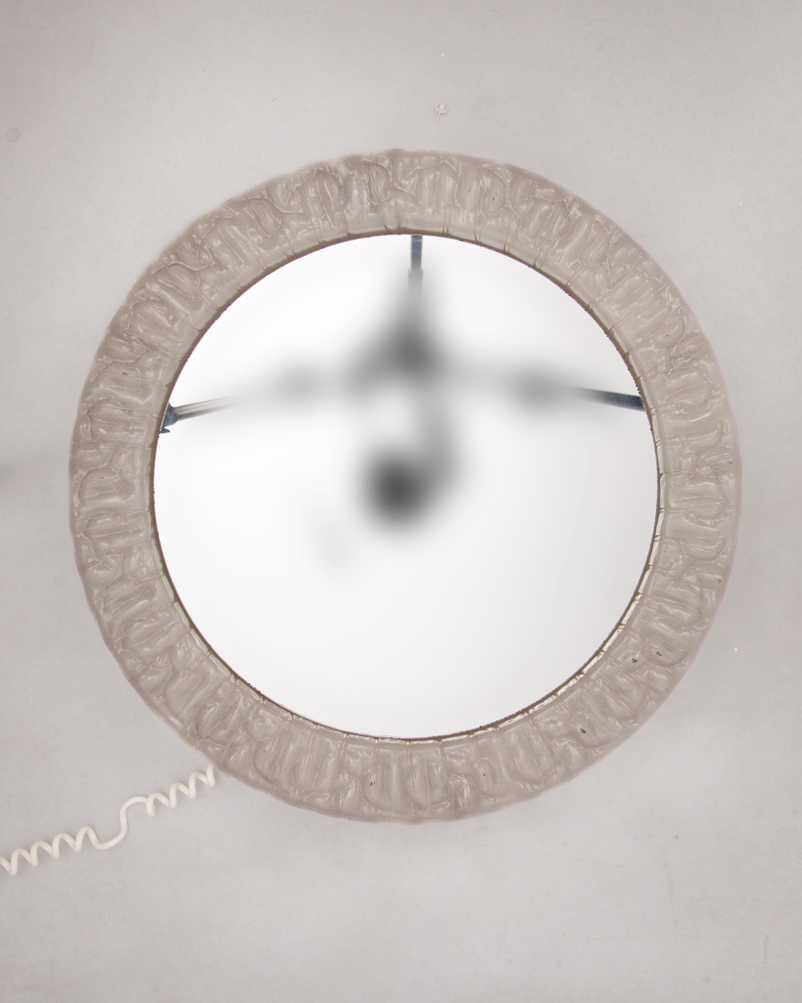 Large round wall-mounted make -up mirror with frosted-ice relief lucite translucent frame, illuminated with ten bulbs, also suitable for LED, attached to a scissor extension metal pull-out  system to bring the mirror closer to you a perfect make-up