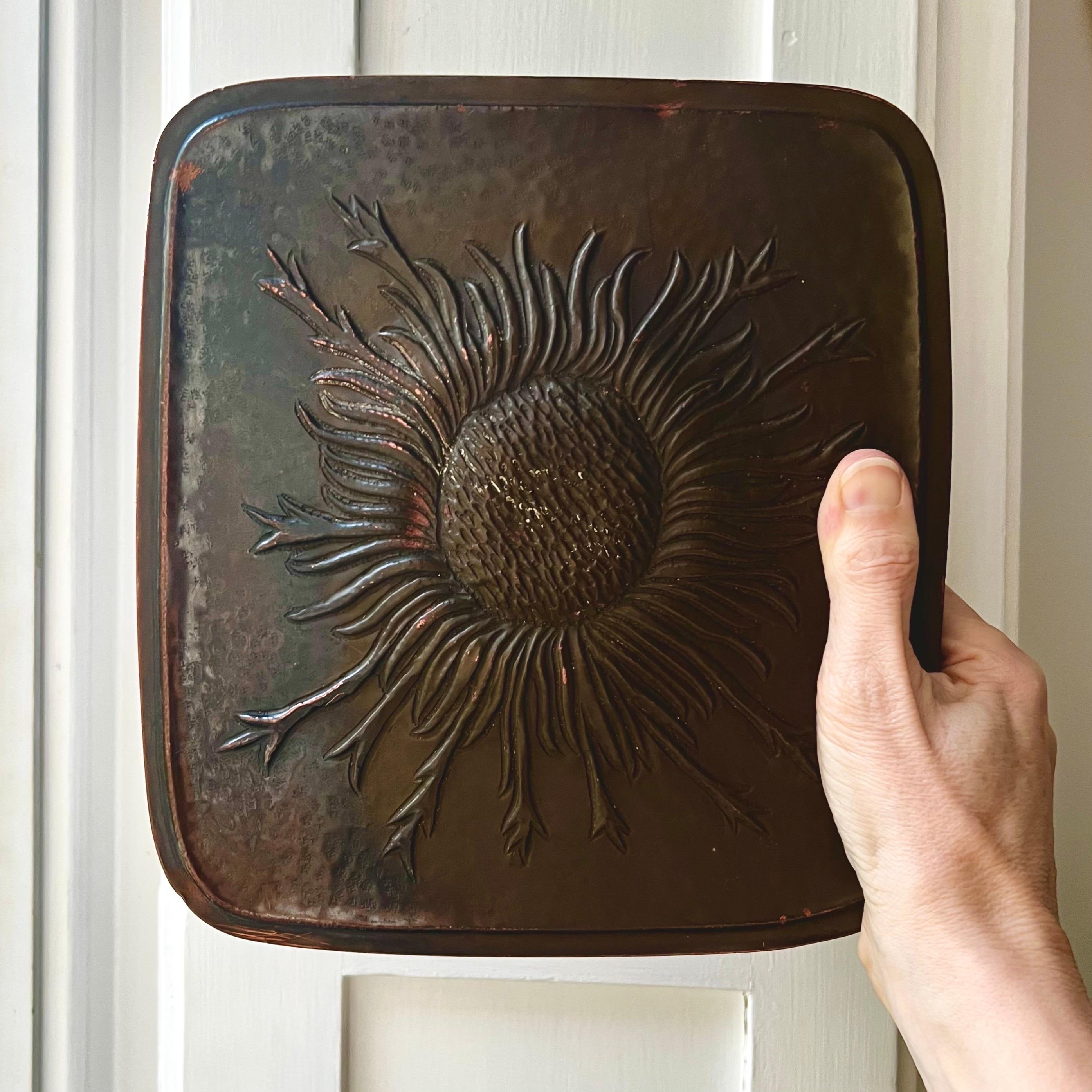 A large push-pull door handle with raised sunflower design, made of patinated and hammered copper repoussé, probably over wood. Found in Germany, mid-20th century.

An unusual piece, which looks to be hand-crafted, in good vintage condition. Nicely
