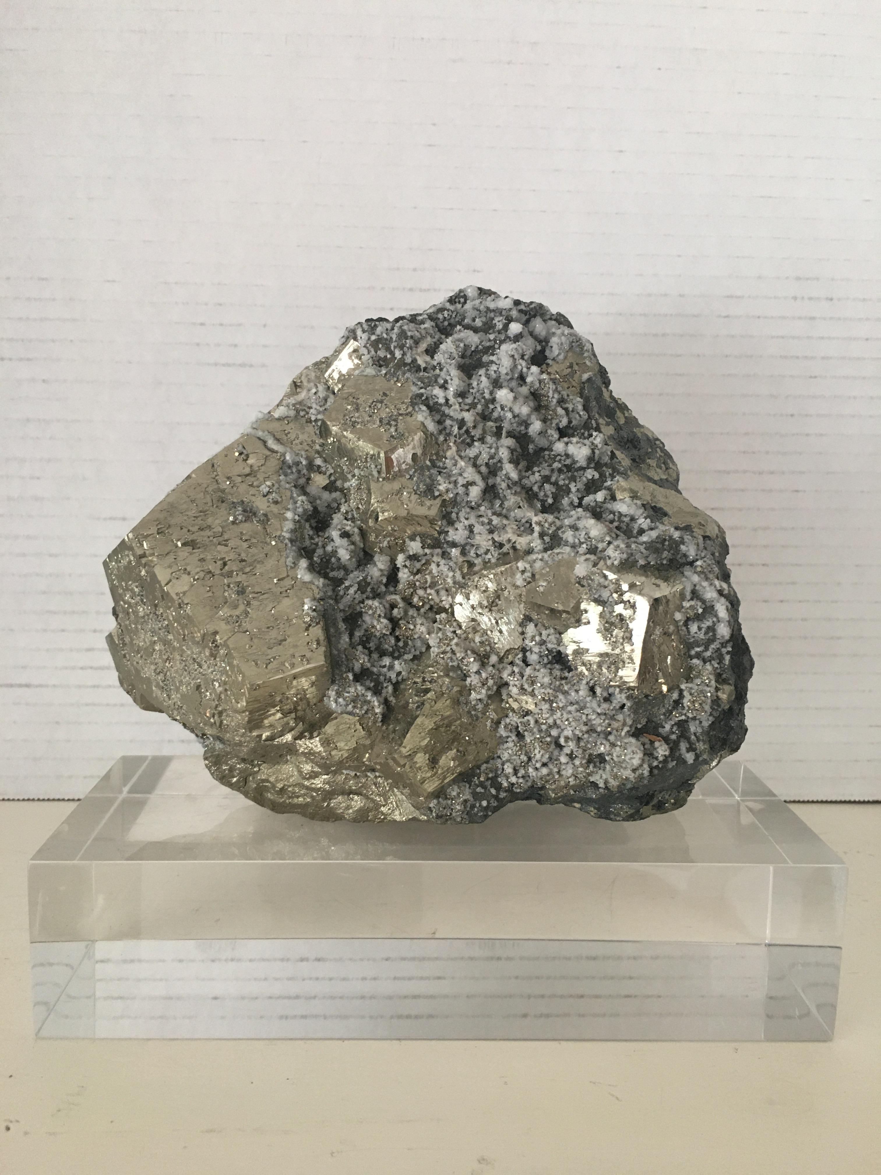 A large pyrite with quartz crystals specimen on custom Lucite base.
