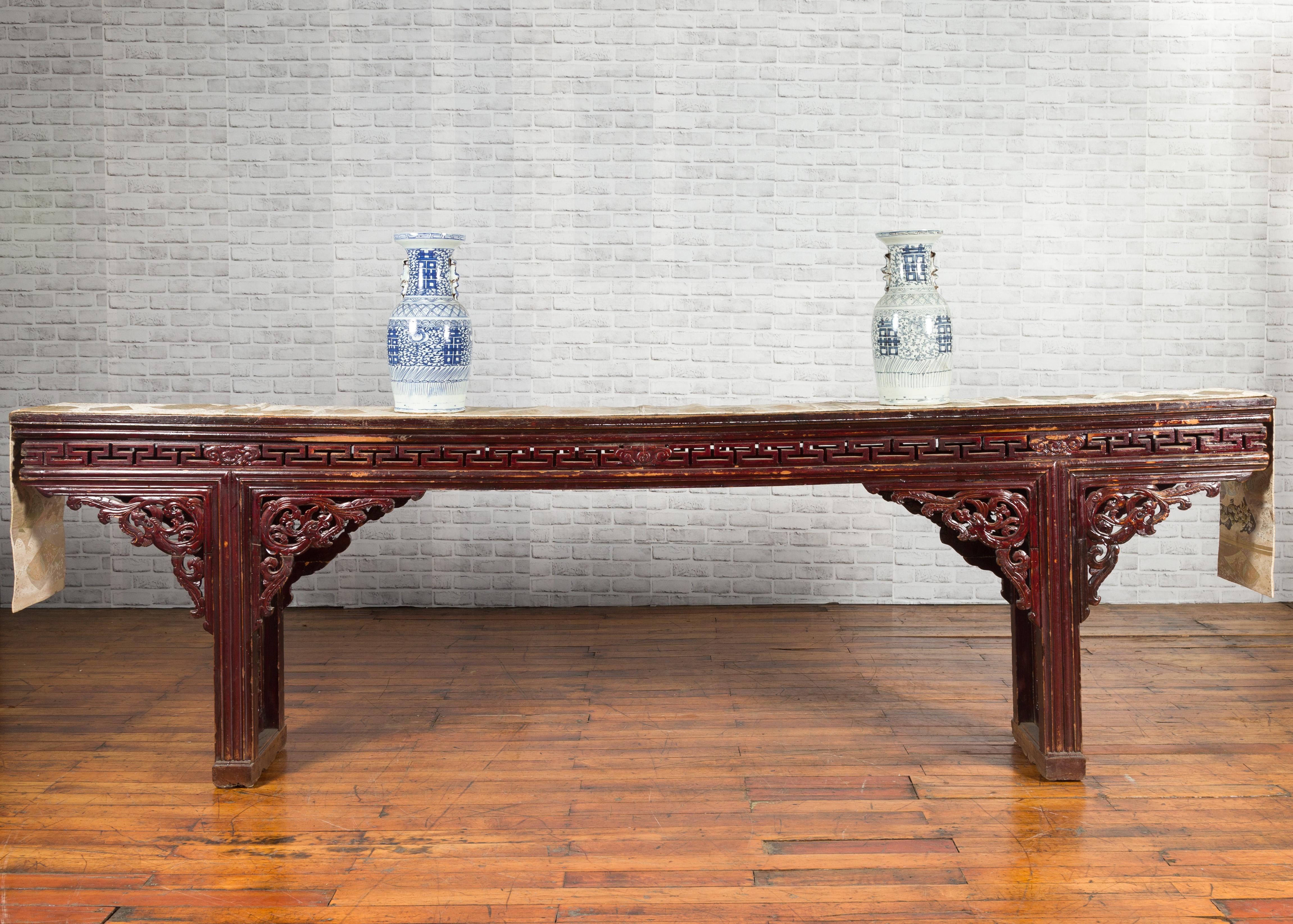 A large Chinese Qing Dynasty period altar console table from the 19th century, with fretwork and dragon motifs. Created in China during the Qing Dynasty period, this large altar console table features a narrow top sitting above an elegant apron