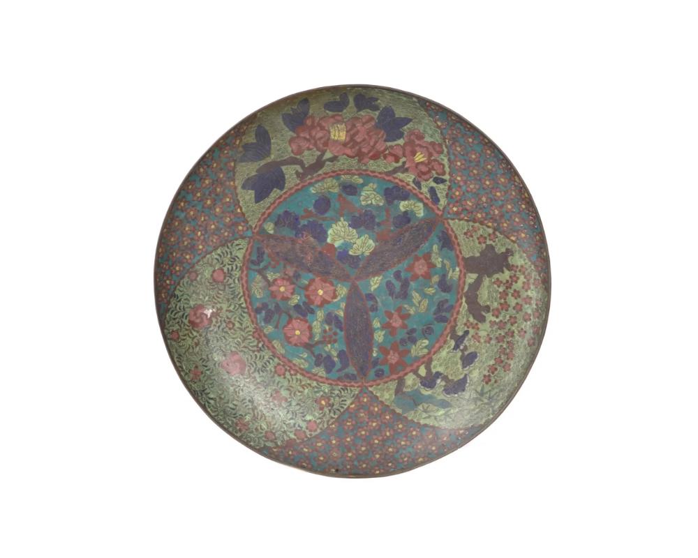 A large rare antique, Meiji era, Japanese enamel over copper plate or charger. The interior of the plate is made in a symmetrical design, adorned with polychrome enamel medallions featuring floral, foliage, cloud, and foliate scroll ornaments on the