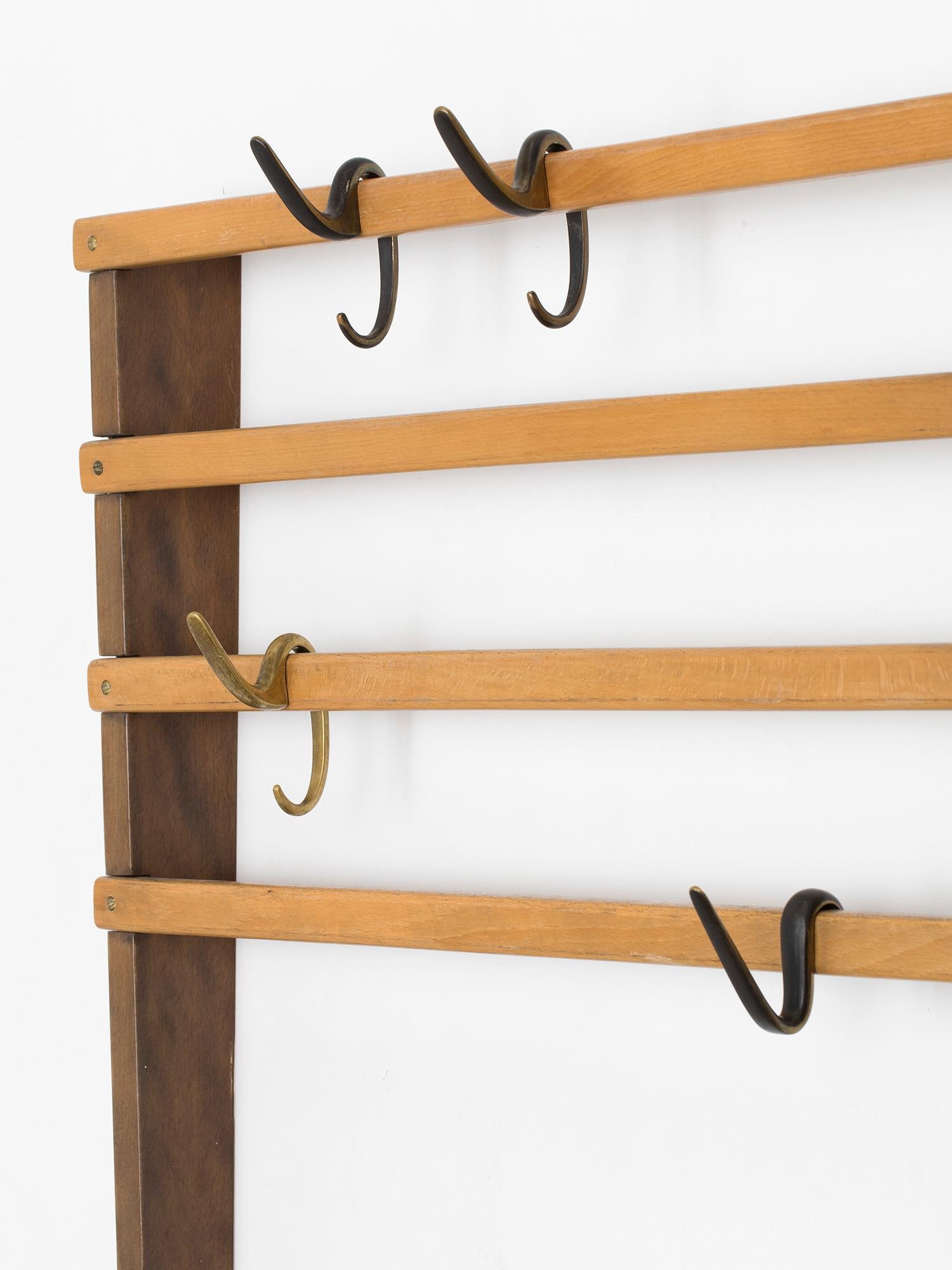 Large and rare Carl Auböck wall-mounted coat rack in two-toned natural and stained maple with nine movable brass hooks of three types. It is in excellent vintage condition. Made at the Auböck Werkstatte in Austria in the 1950s.