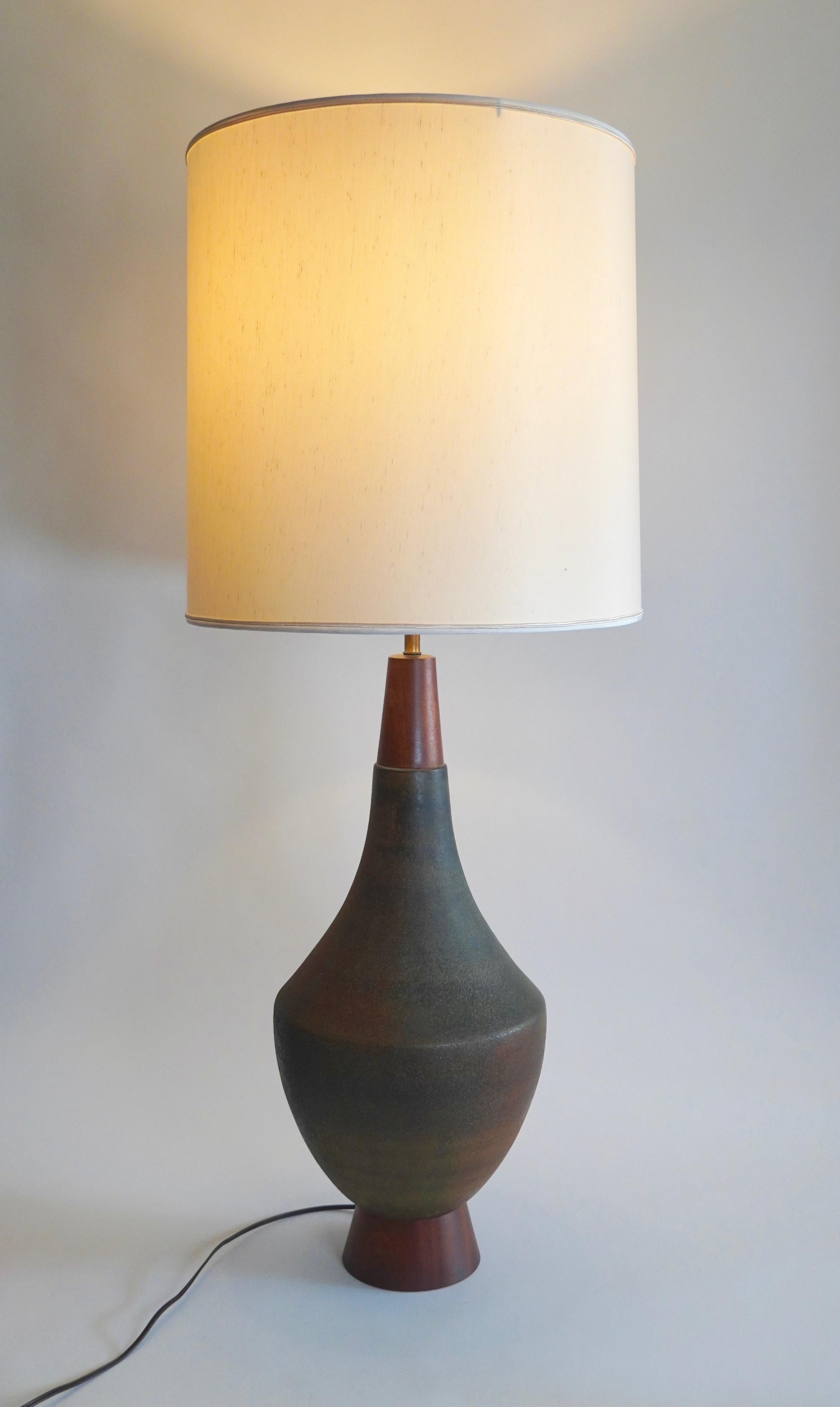 Large in scale is this rare ceramic and walnut table lamp designed by Aldo Londi for Bitossi of Italy. Having a multi-colored soft volcanic glaze of burnt oranges and greens resting on a walnut base. The hardware is brass and is fully working, the