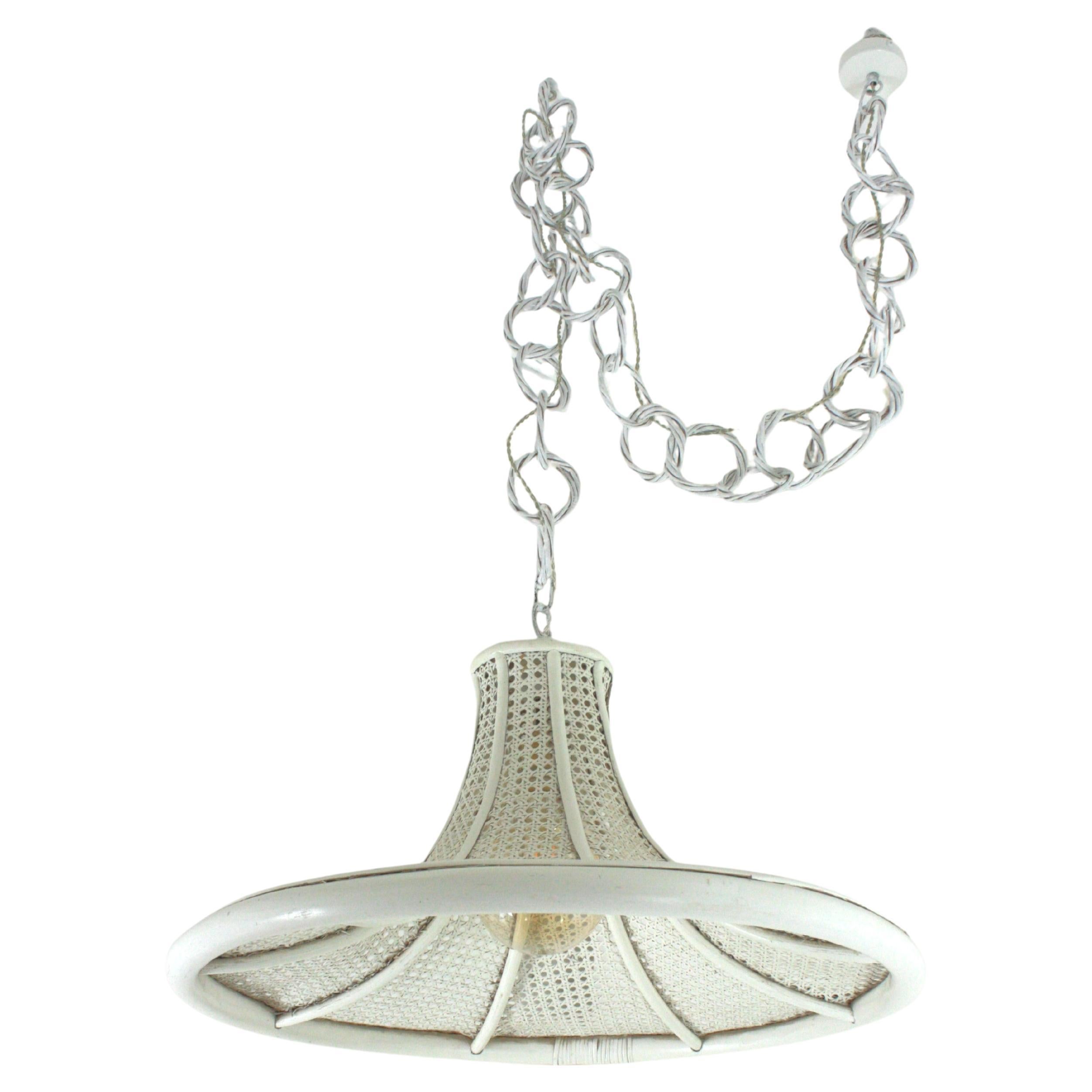 Pendente o lampadario a forma di pagoda in rattan e filo di vimini in patina bianca. Francia, anni '60.
Questa lampada a sospensione di metà secolo presenta un grande paralume conico in vimini con canne di rattan di bambù e un anello di rattan nella