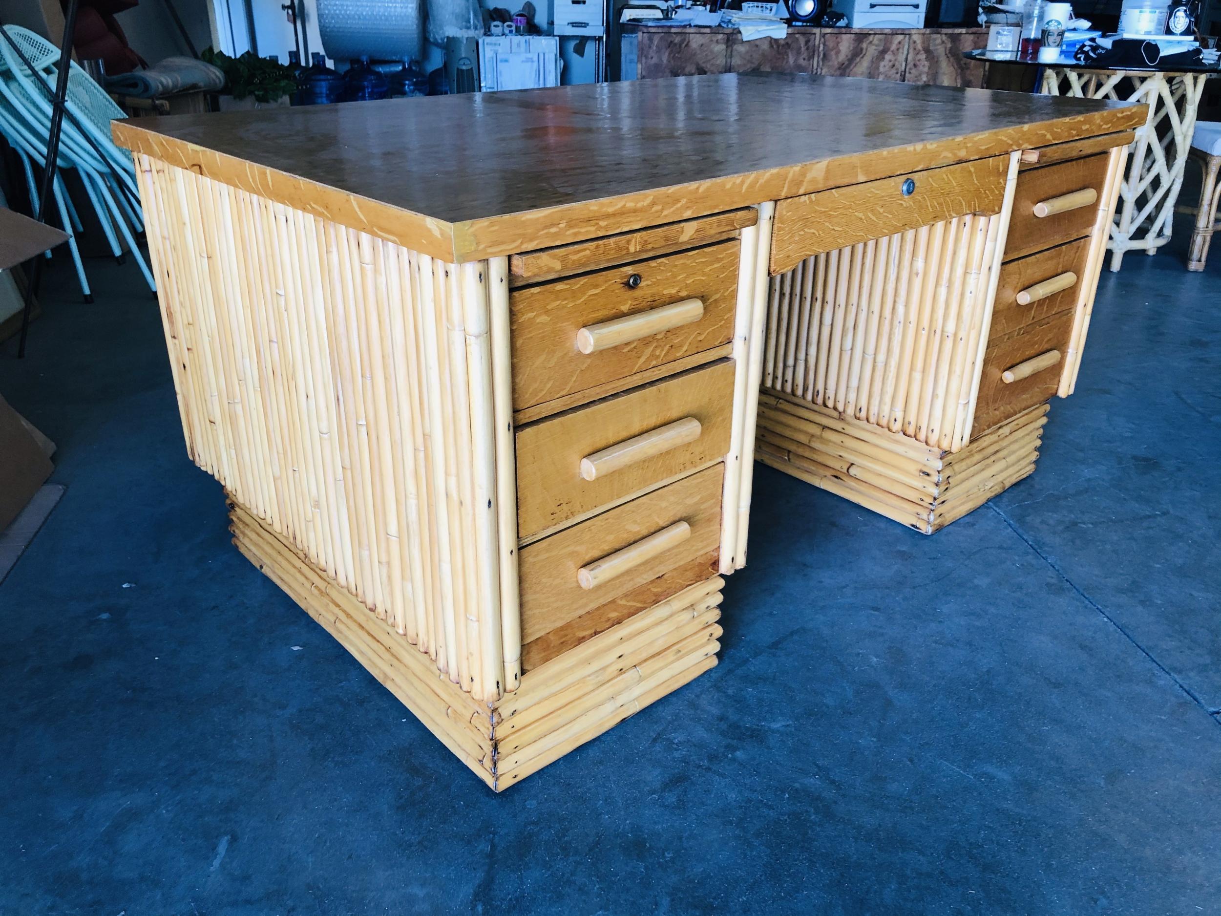 Restored very large stacked rattan desk, with Filipino mahogany top. Drawer fronts, side panels, and top. The desk features a center drawer and six side drawers. Beautiful stacked rattan legs race from the top to the bottom, creating a great modern