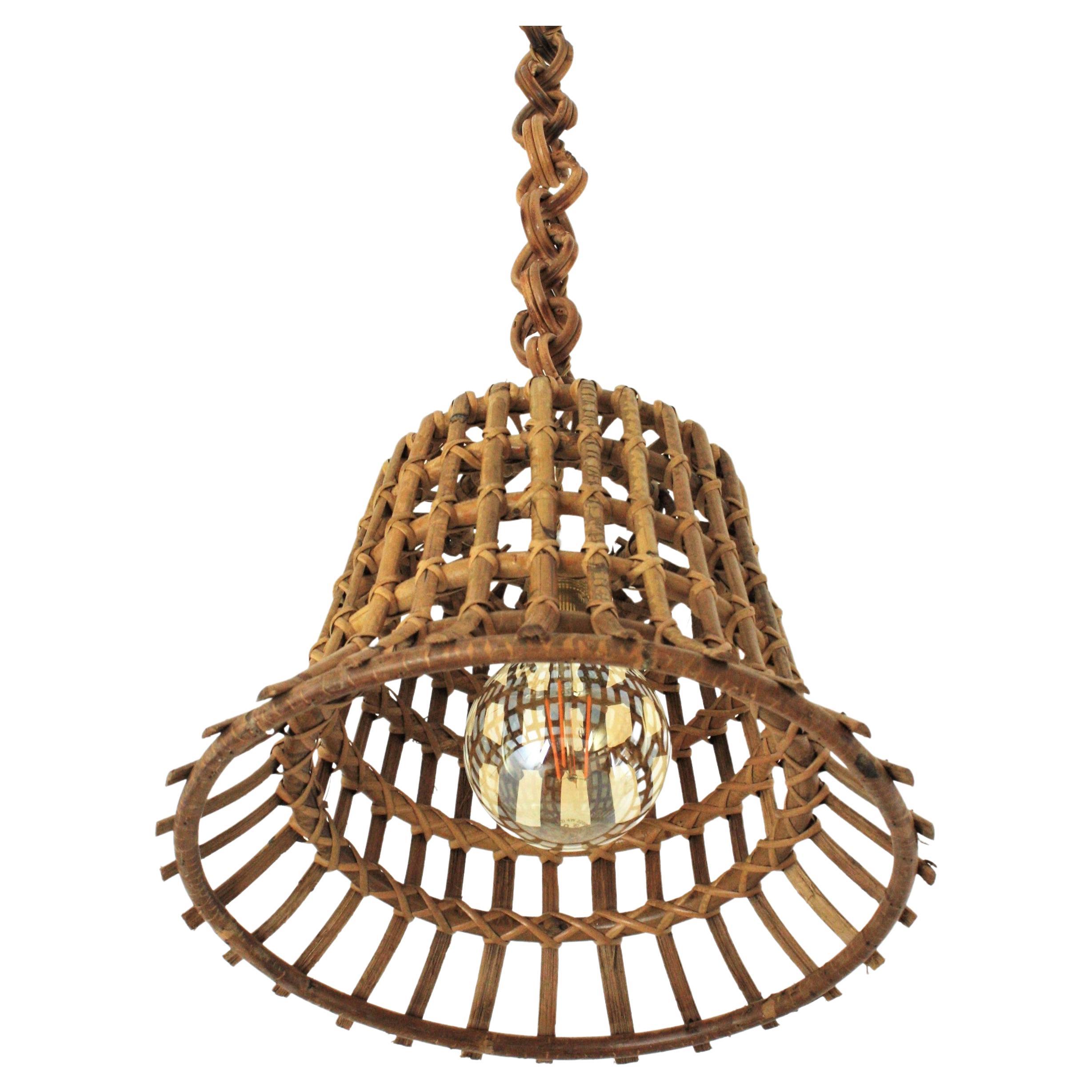 French Riviera large pendant light in rattan with grid basket design, 1960s
This gorgeous suspension lamp has a basket or bell shape lampshade made of an intrincate of rattan canes as a grid. It hangs from a chain with double rattan round links.