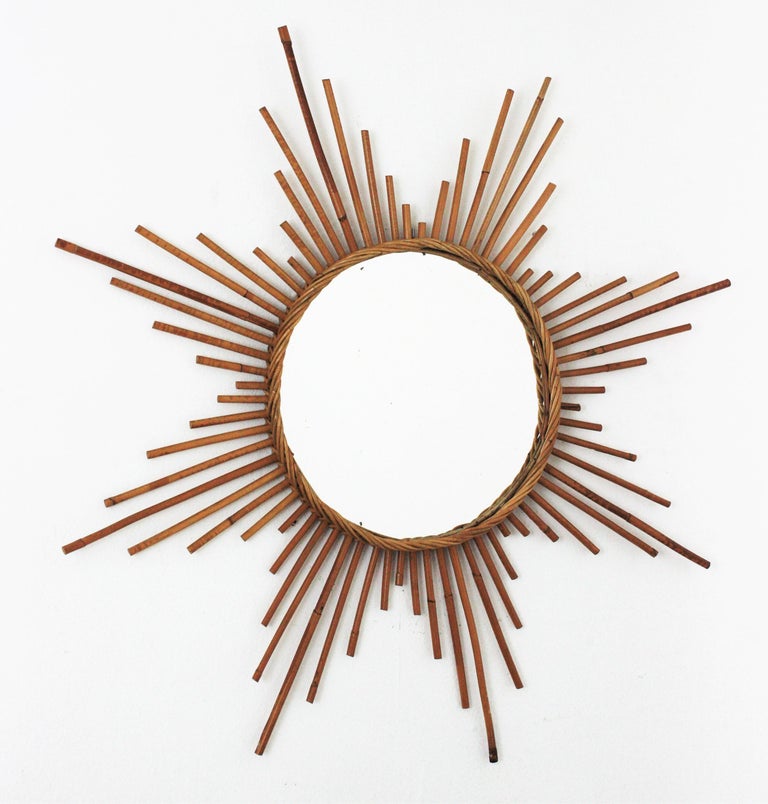 1960s French Riviera Mid-Century Modern large rattan starburst mirror or sunburst mirror.
A beautiful handcrafted rattan star shaped mirror with a braided rattan frame surrounding the central glass. The detailed intrincate of thinner rattan canes