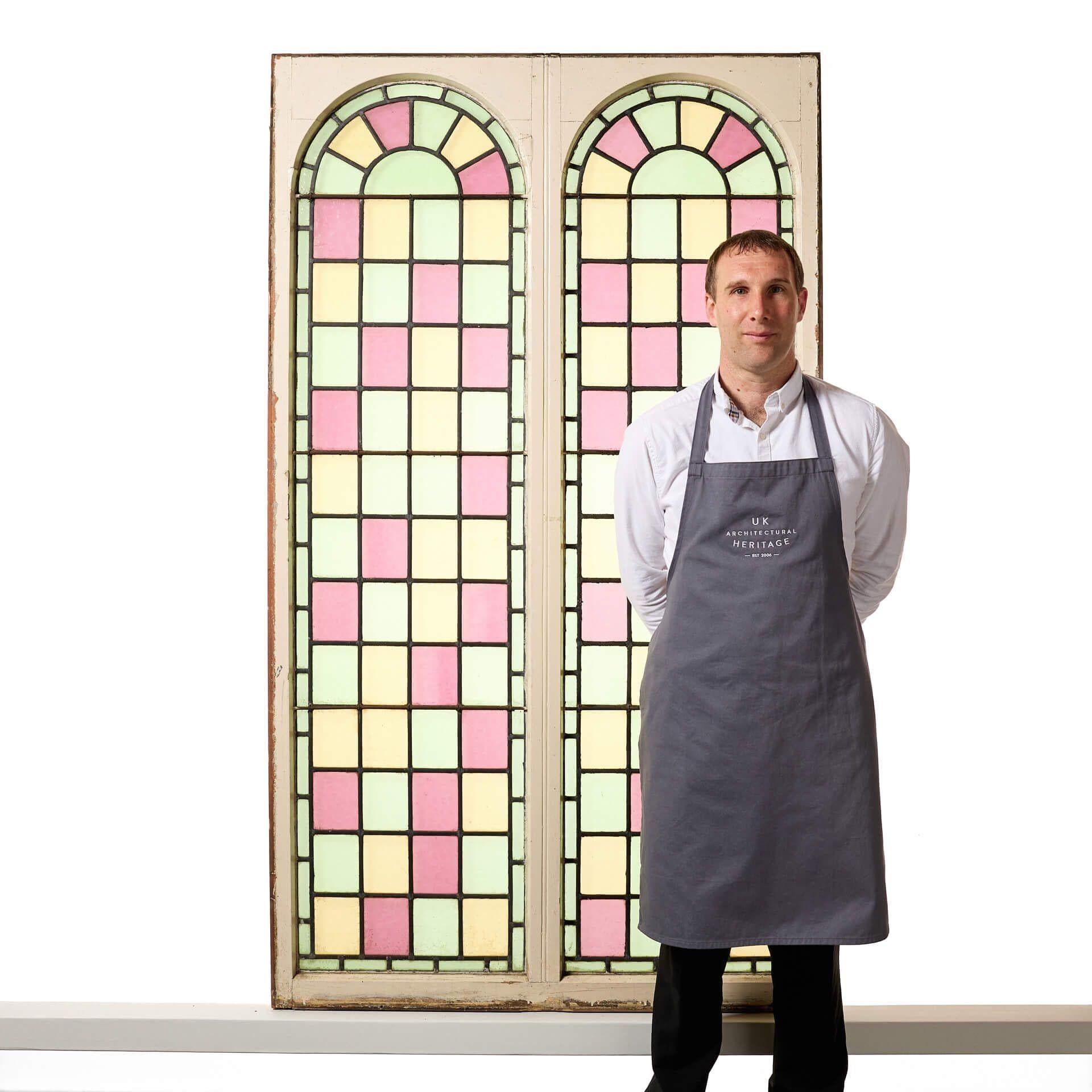 A pair of large reclaimed arched stained glass double windows, sourced from a chapel built in 1850. Tall in scale, these colourful windows are currently fixed into original pine frames. Dating to circa 1880, the panels are decorated in pastel