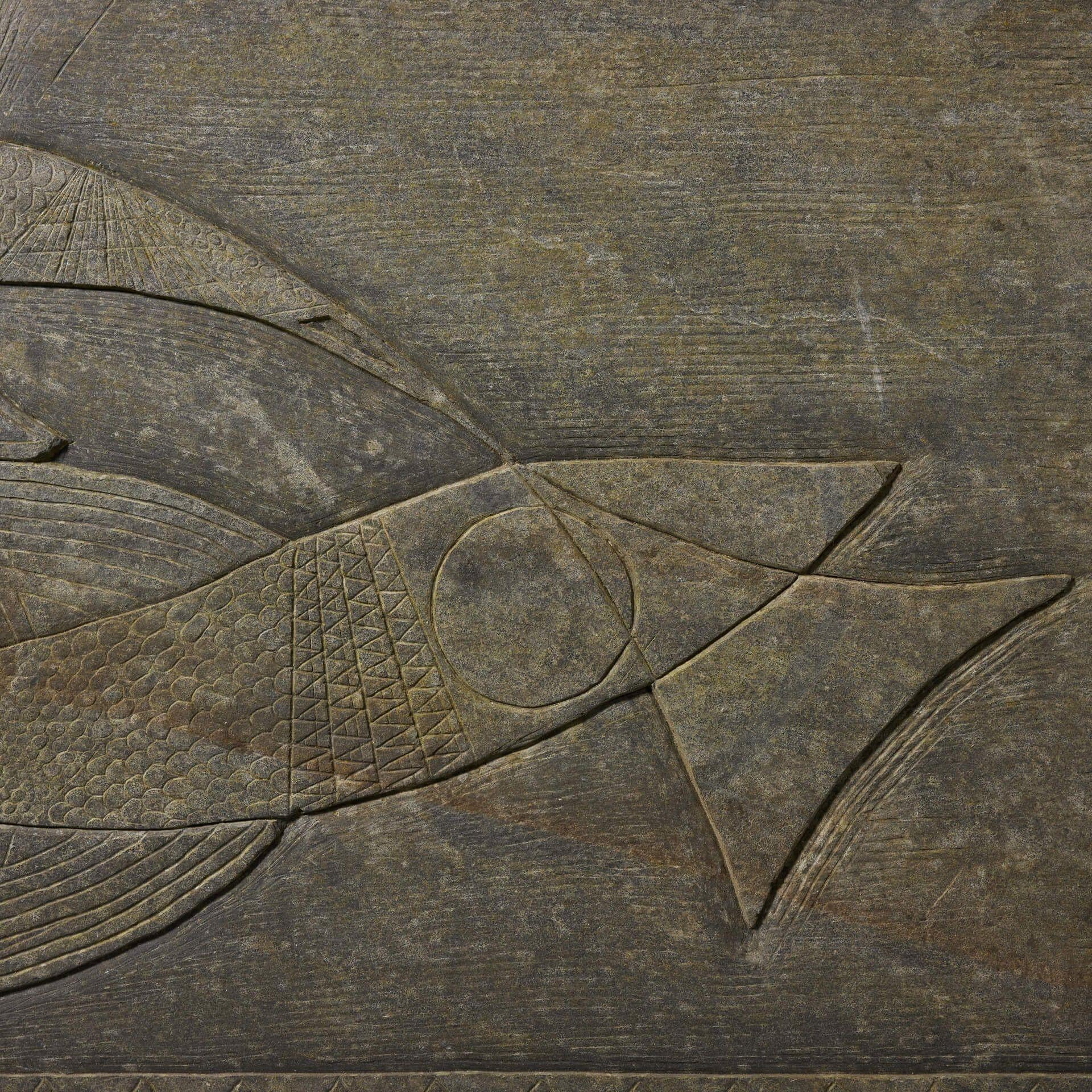 Eine große, geschnitzte Schieferplatte, die stilisierte Fische darstellt. Diese Tafel aus dem 20. Jahrhundert zeigt zwei abstrakte Fische, die von Hand auf glatten, dunklen Schiefer geschnitzt wurden. Das Paneel im modernen Stil der Jahrhundertmitte