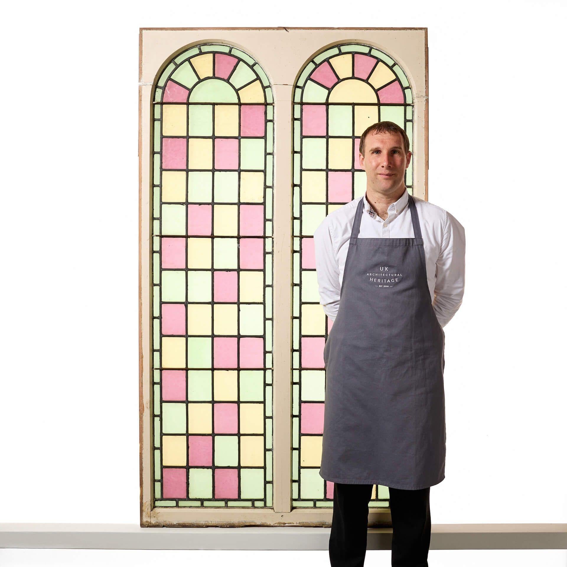 A pair of antique large reclaimed arched stained glass double windows, sourced from a chapel built in 1850. Tall in scale, these colourful windows are currently fixed into original pine frames.

Dating to circa 1880, the panels are decorated in