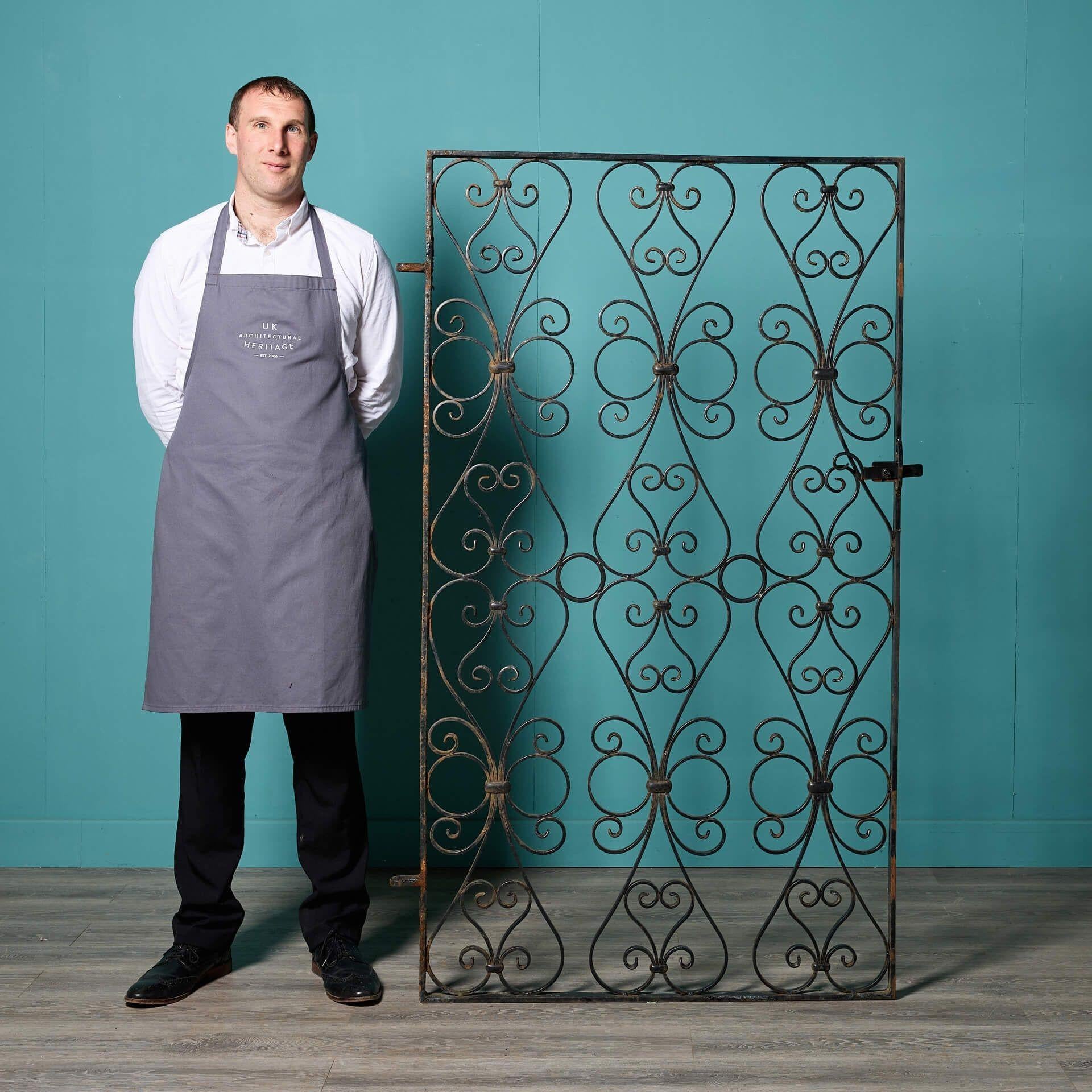 A beautiful and large-scale reclaimed English wrought iron gate with repeating scrolling patterns, traditionally handcrafted by a talented 20th century blacksmith. Victorian in style, this large wrought iron gate is an elegant addition to properties