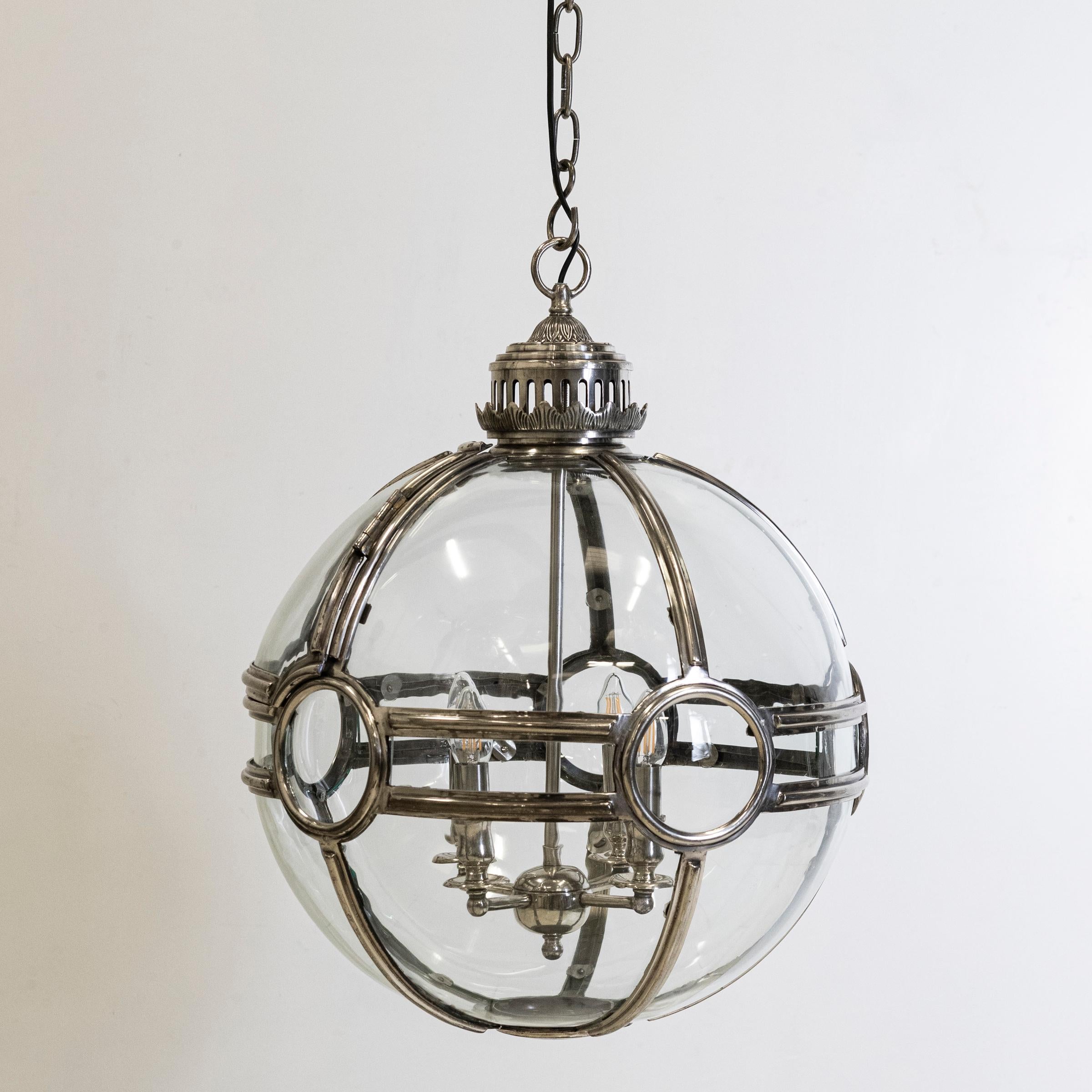 A large and impressive globe light whose design is an enduring classic. The sphere delivers an opulent light feature for your interior space.

With clear glass panels and elegant metal details. 4 candle bulb holders are suspended from within. These
