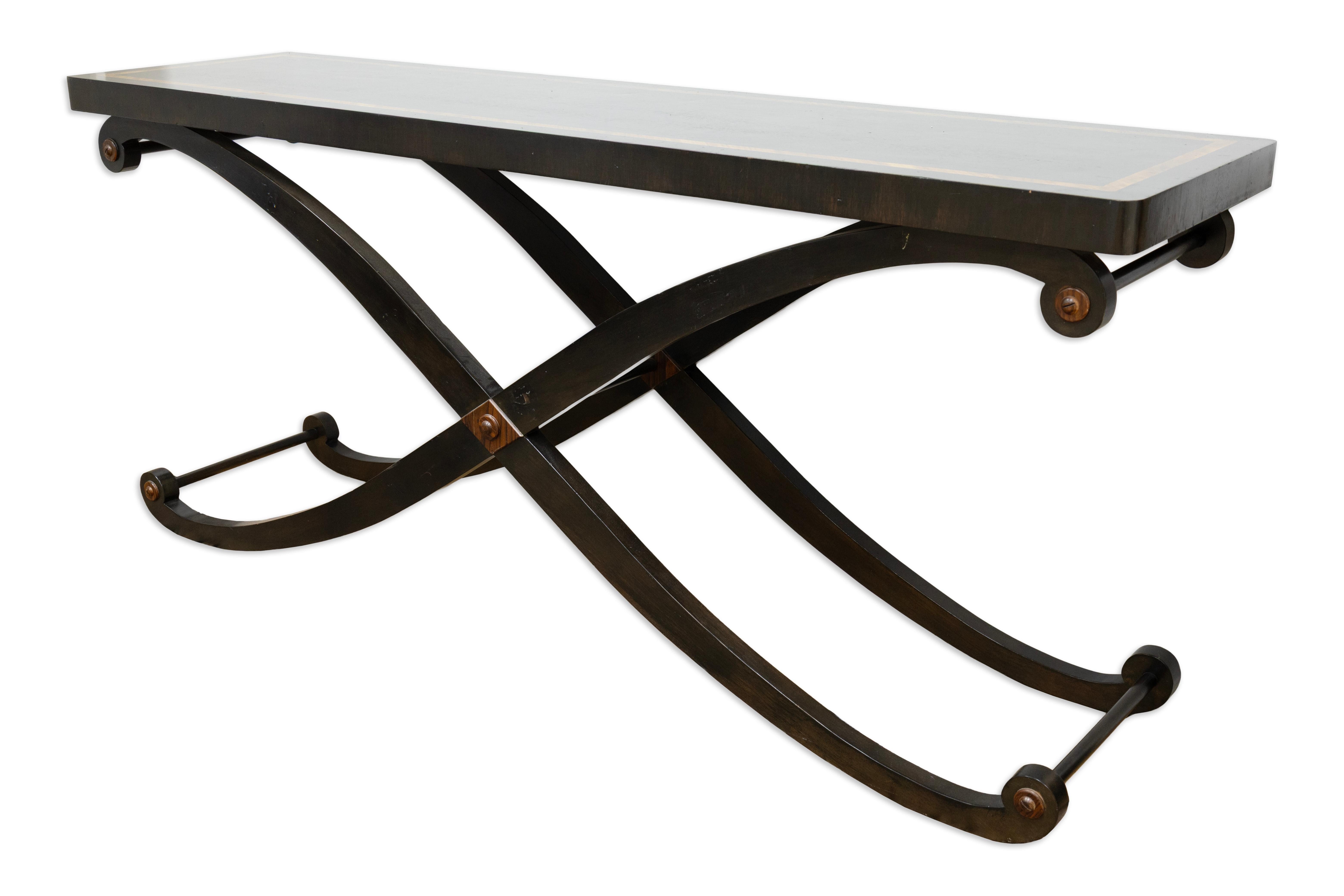 Esta elegante consola tiene un tablero rectangular de madera maciza apoyado en una base curvada con patas cruzadas. La forma escultural de la base combina la fuerza con un diseño fluido, dando a la pieza una presencia equilibrada y arquitectónica.