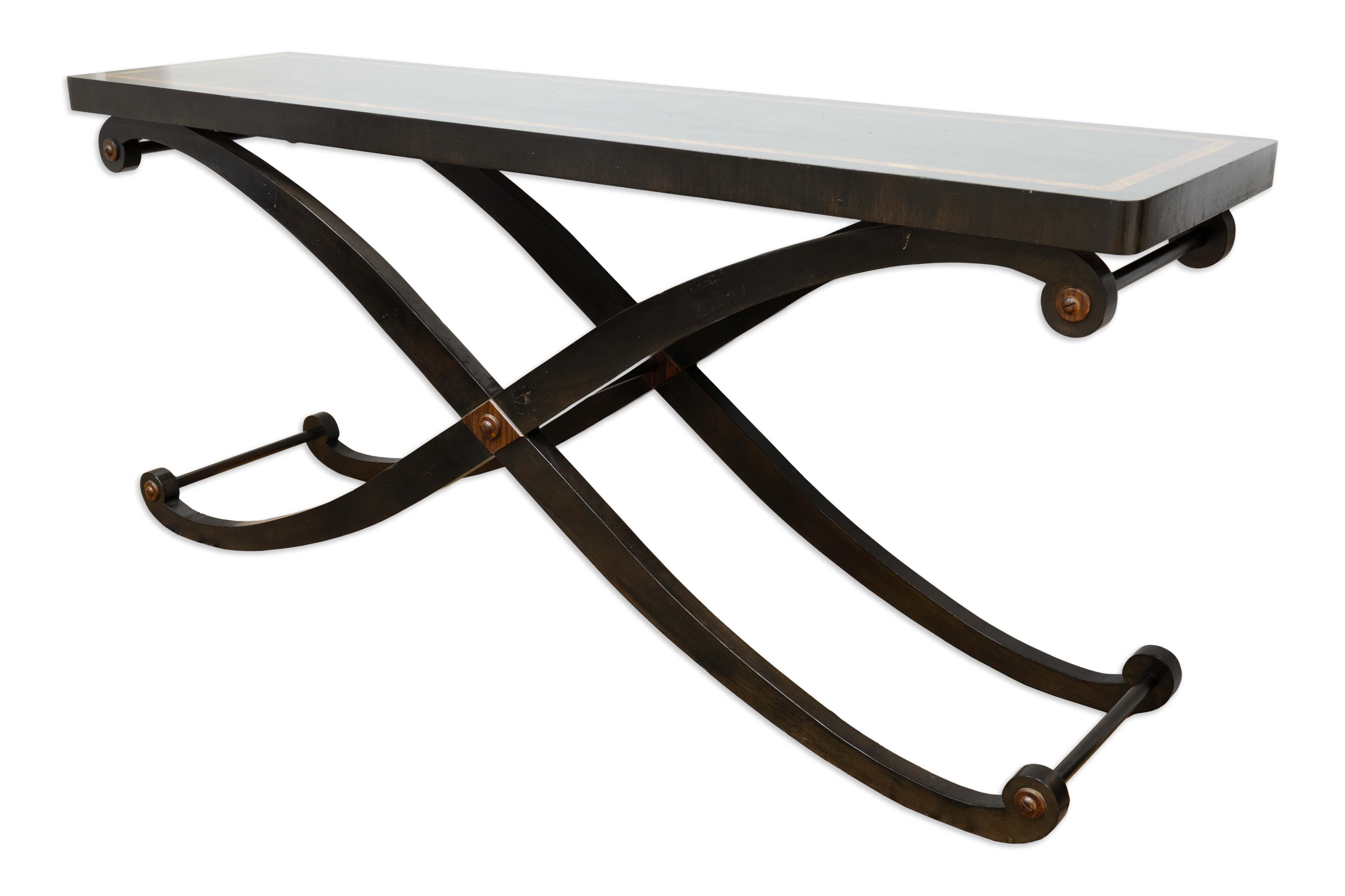 This elegant console table features a solid wood rectangular top supported by a curved base with intersecting cross legs. The sculptural form of the base combines strength with fluid design, giving the piece a balanced and architectural presence.