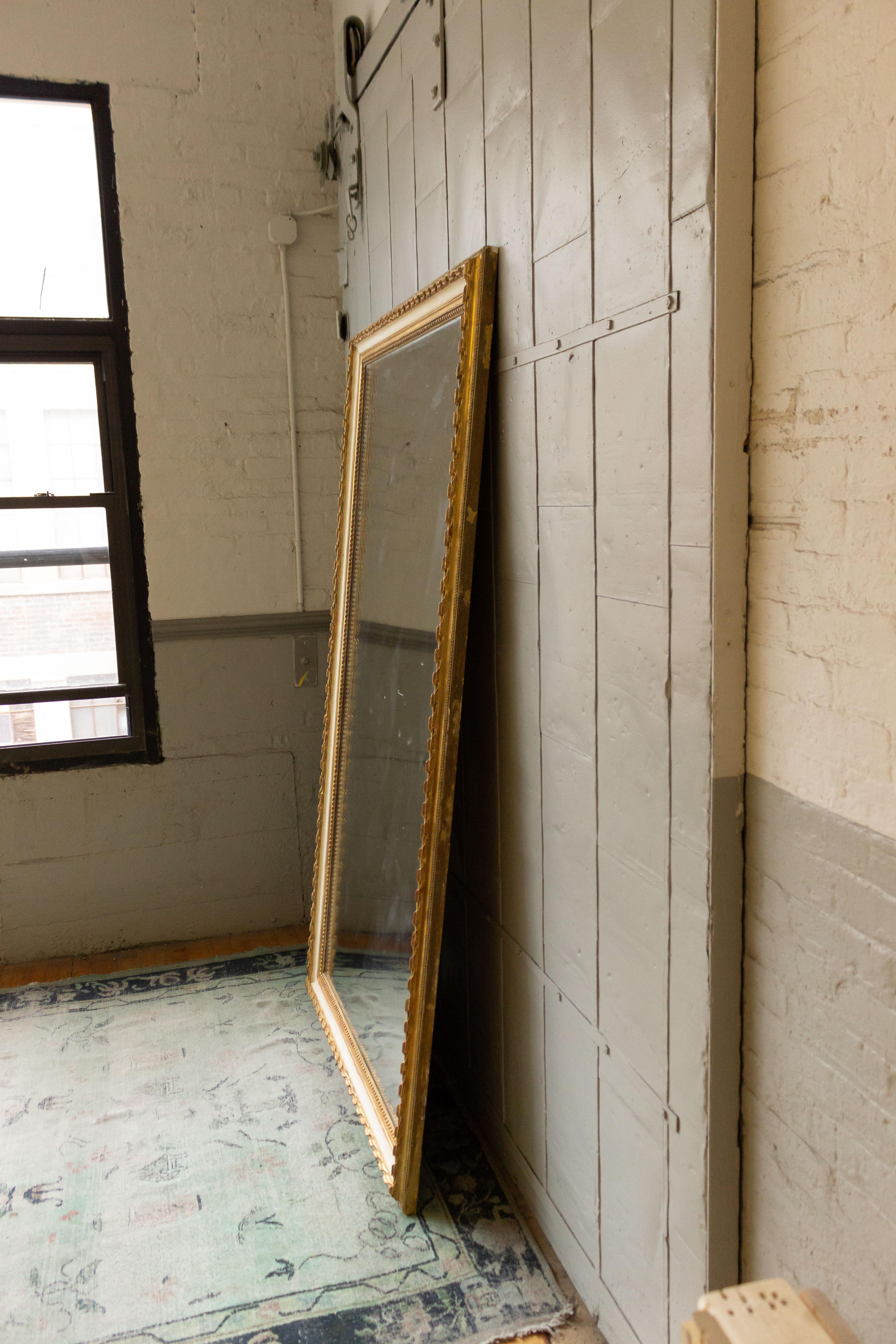 Grand miroir au mercure français du 19ème siècle dans un cadre en bois doré sculpté avec un contraste peint en blanc cassé. Le verre au mercure et le support en bois sont d'origine. Un système de suspension à taquets a été installé à l'arrière du