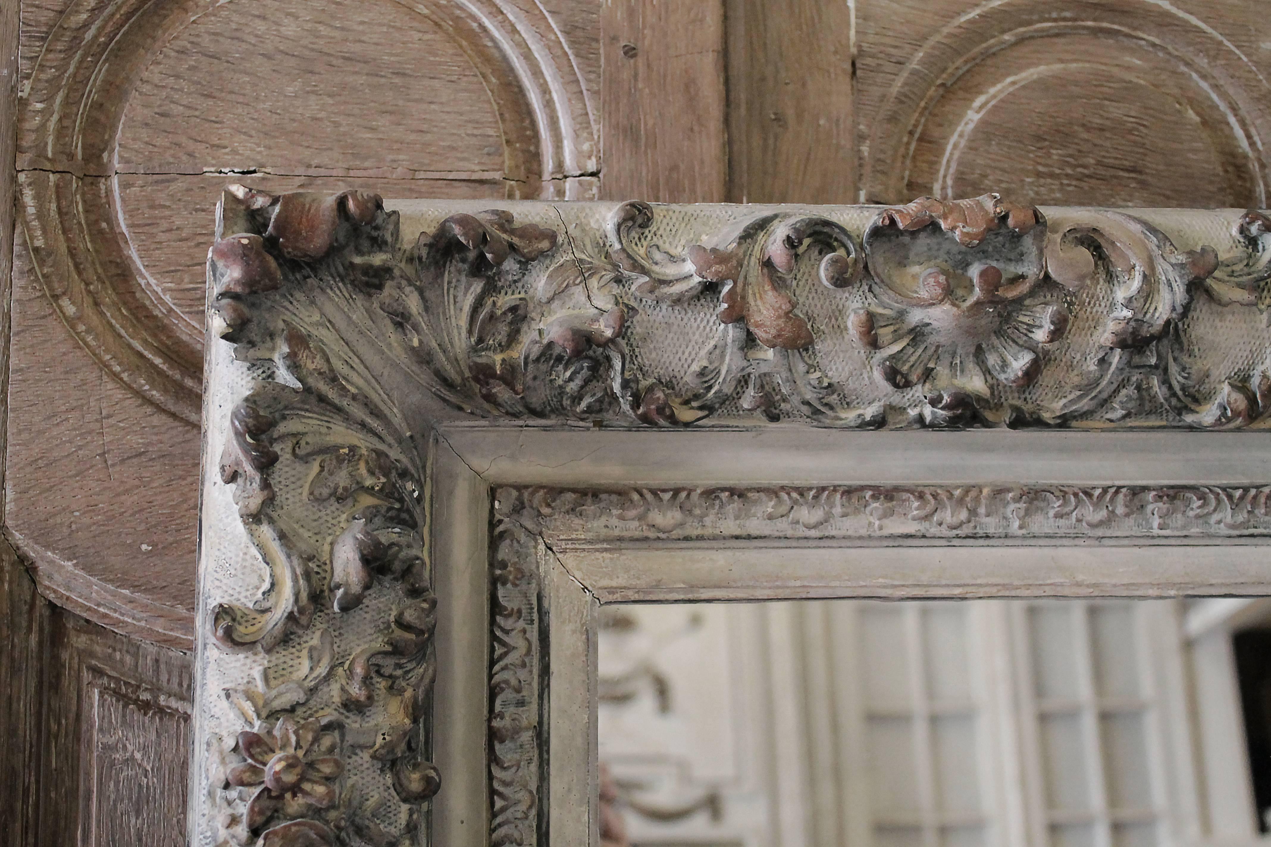 Large rectangular painted carved style mirror.
The frame is wood with a gesso, or plaster decorative front. Some corner areas have chipped edges, as shown in photo, nothing major, very minor. The original finish is a pale putty, or soft grey color,