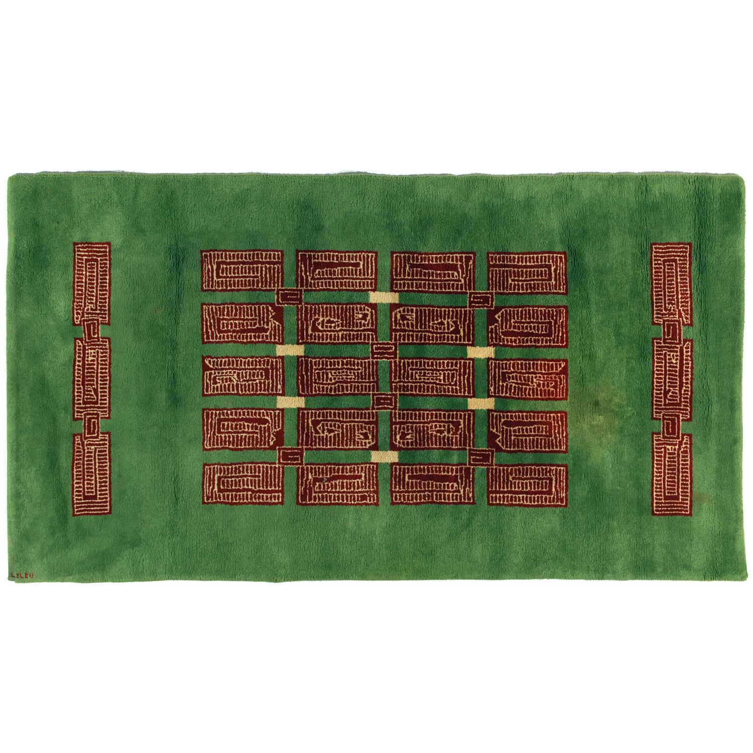 A Large knotted woollen rug with green ground, central decoration forming a geometric composition with brown and sand Aztec designs. Later lining in jute canvas. Signed 