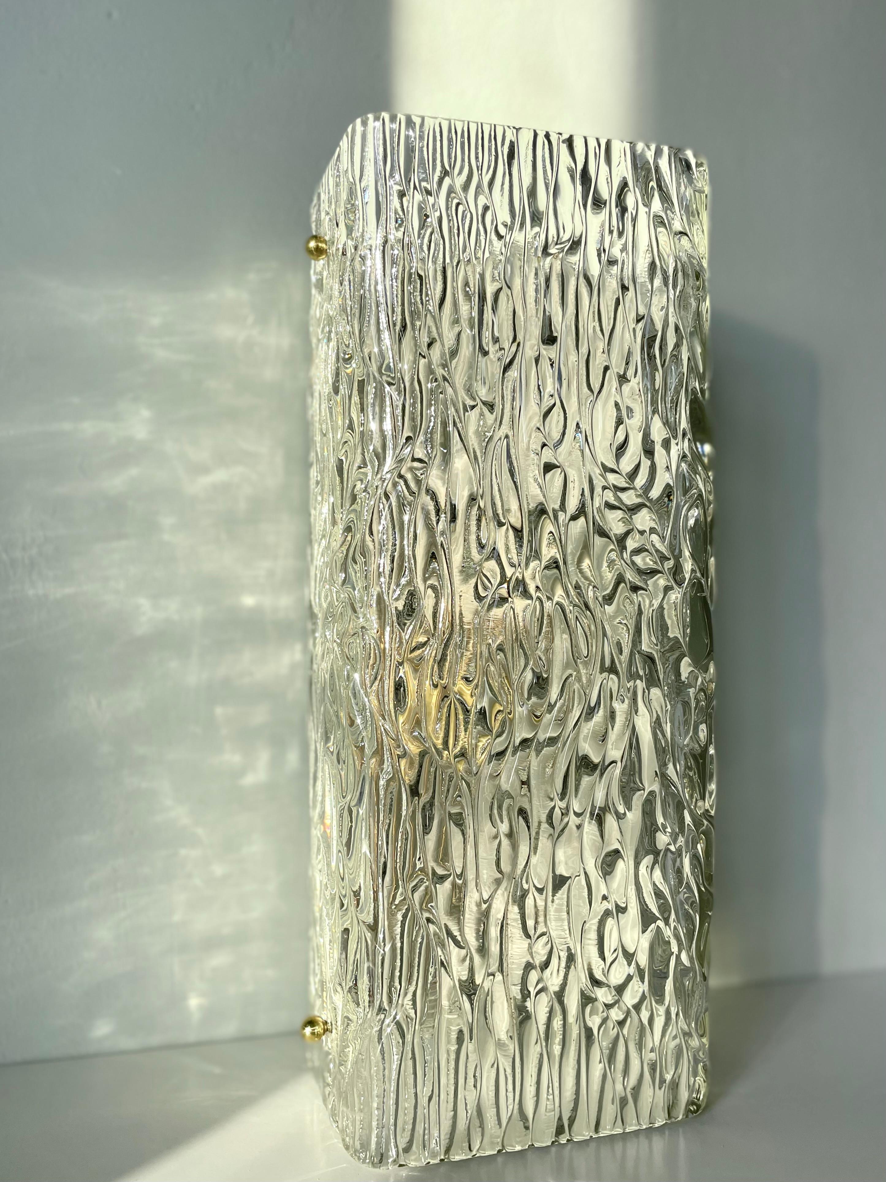 Large European rectangular Hollywood Regency midcentury crystal elongated wall light with shiny brass details manufactured in the 1950s. Clear smooth textured crystal art glass on white lacquered metal mount with two fittings for E14. Wired with